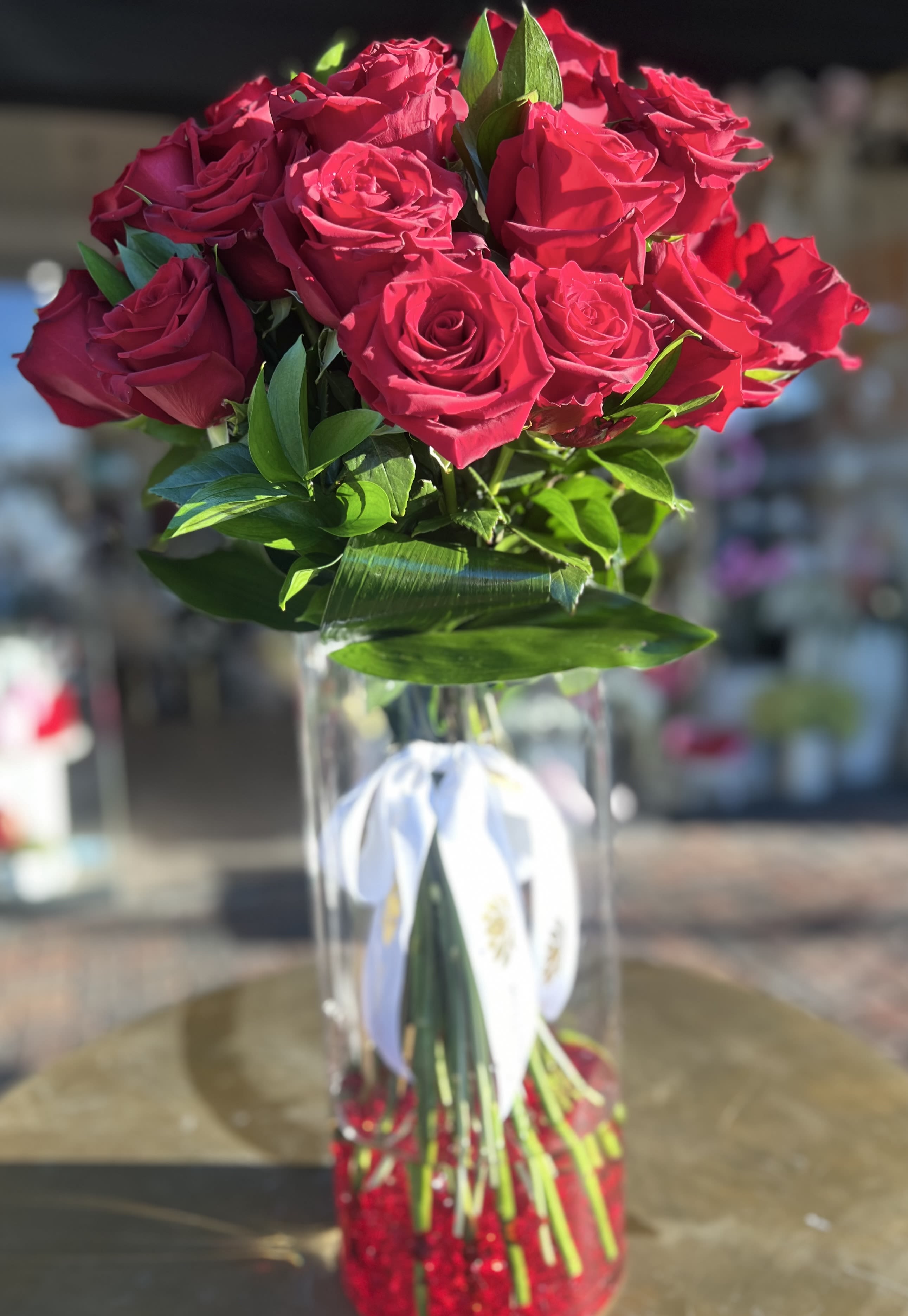 Bouquet of red roses in a clear glass vase with a white ribbon