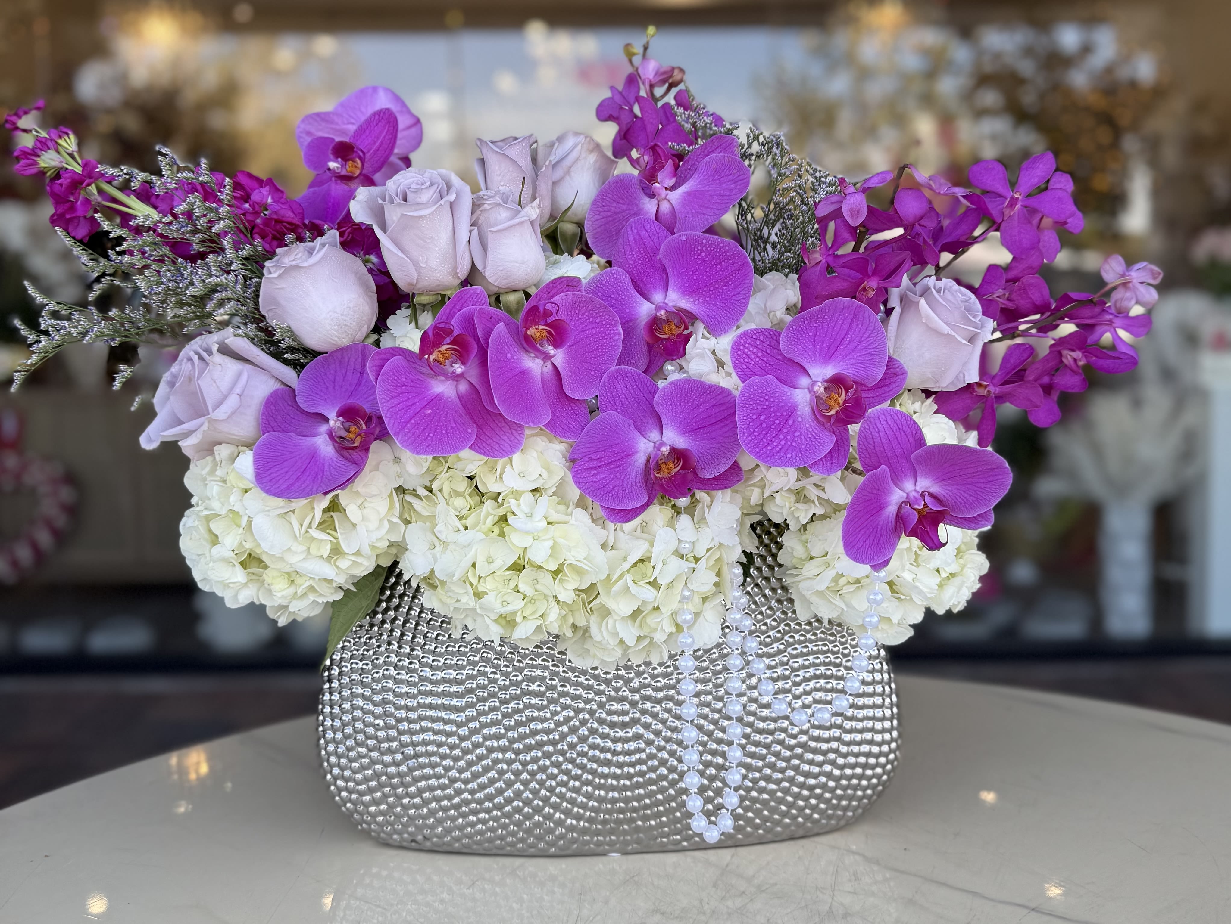 Purple orchids and pale roses in a silver textured vase