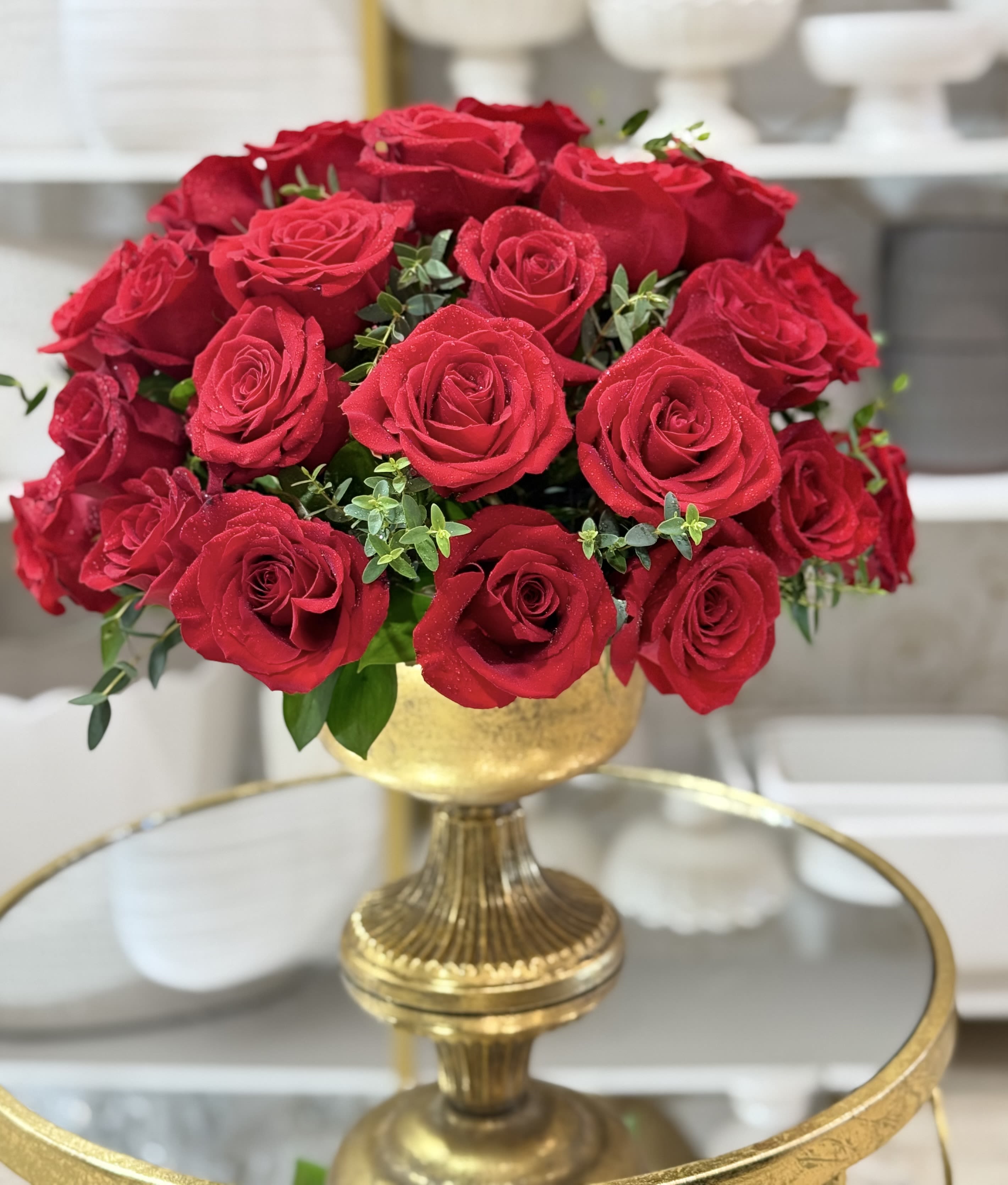 Red roses arranged in a gold pedestal vase