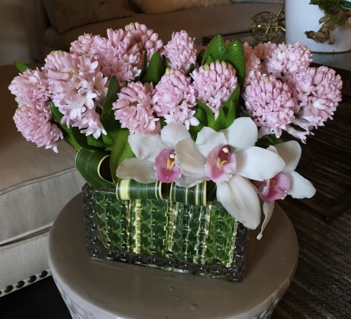 Pink flowers and white orchids arranged in a green glass vase