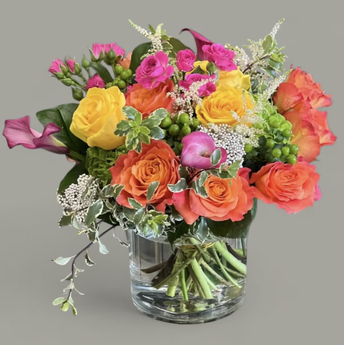 Colorful bouquet of roses and calla lilies in a glass vase