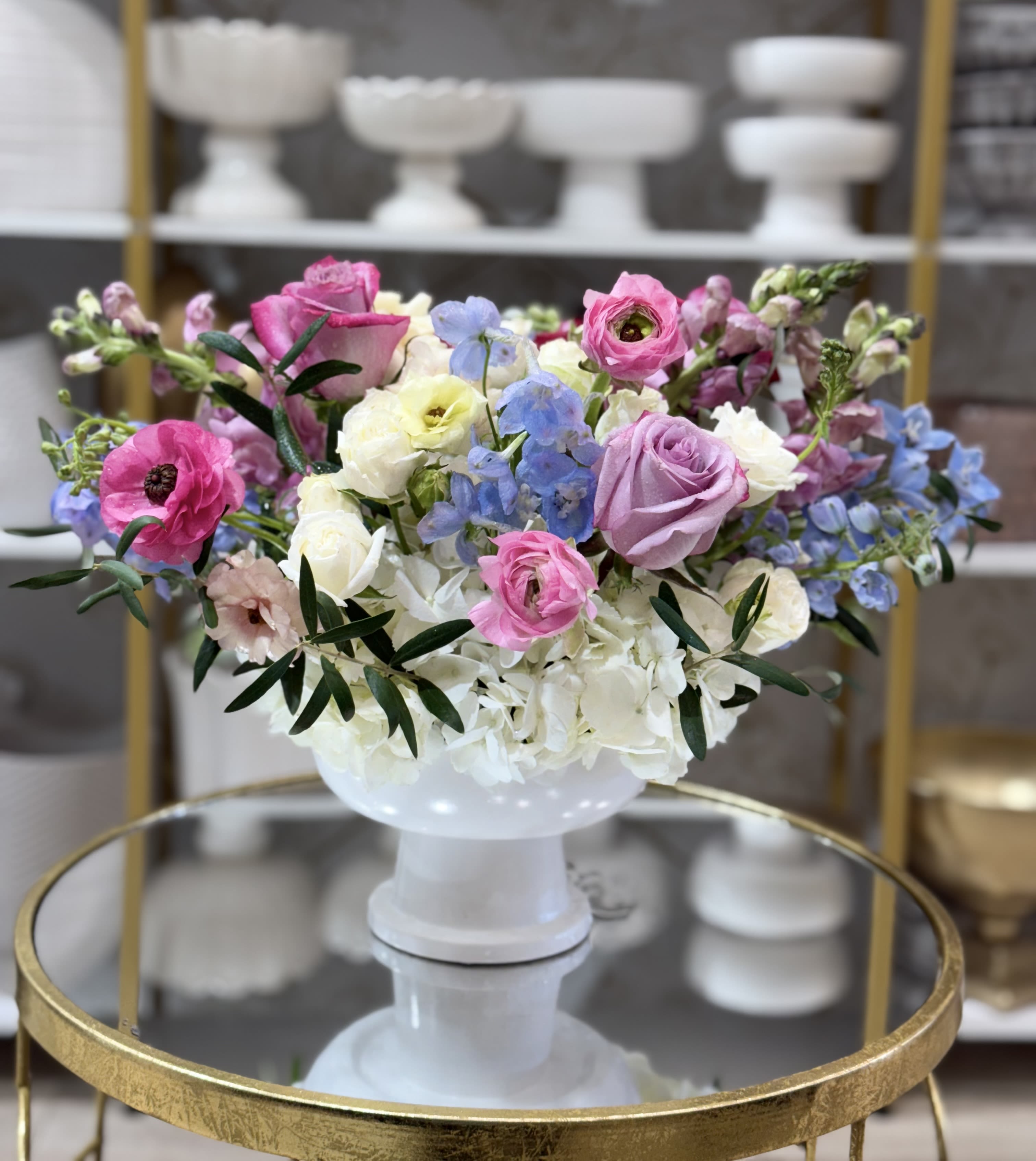 Mixed pastel flower arrangement in a white pedestal vase