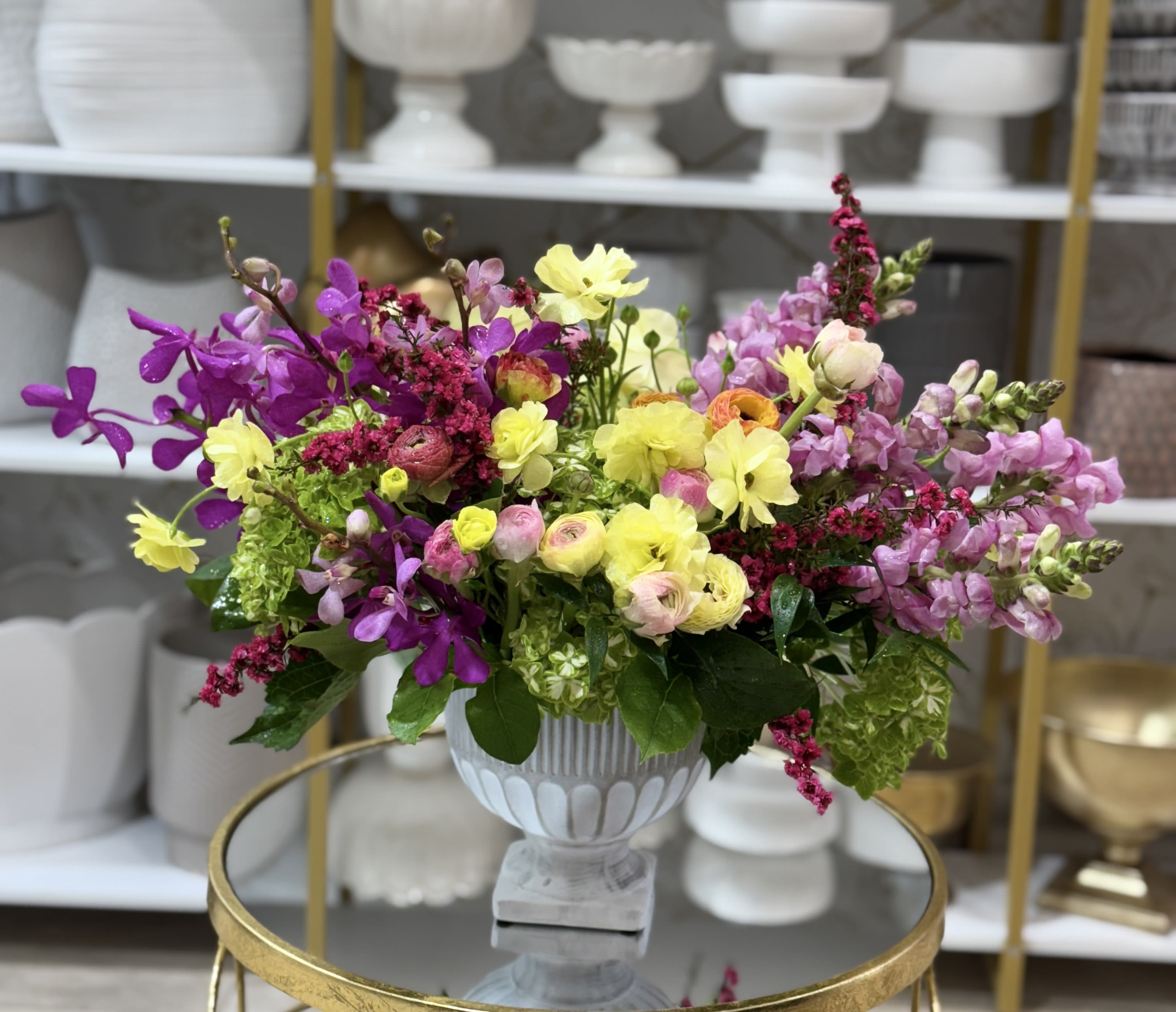 Colorful mixed flower arrangement in a white pedestal vase