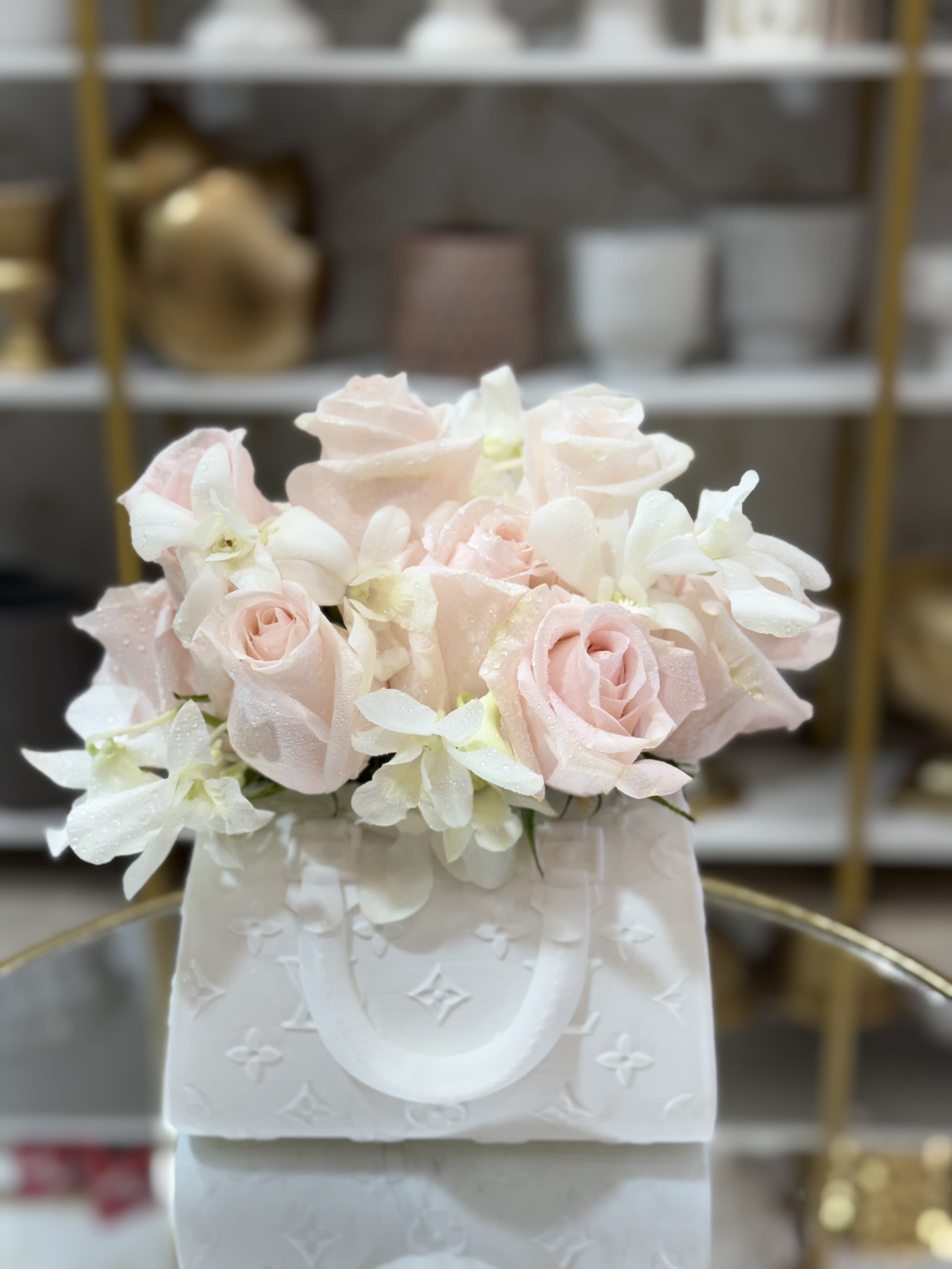 Blush pink roses and white orchids in a white gift bag