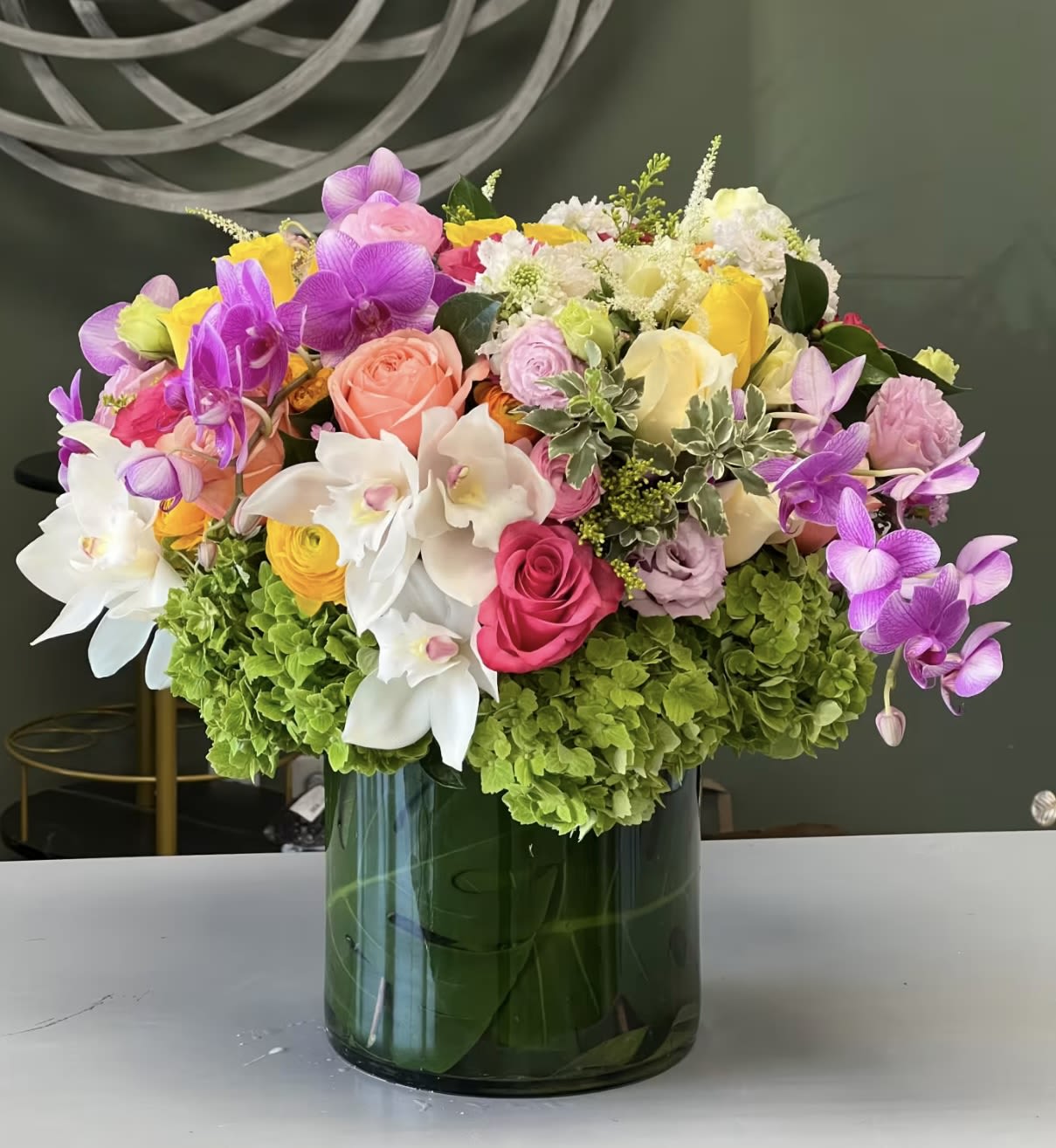 Colorful bouquet of orchids, roses, and hydrangeas in a glass vase
