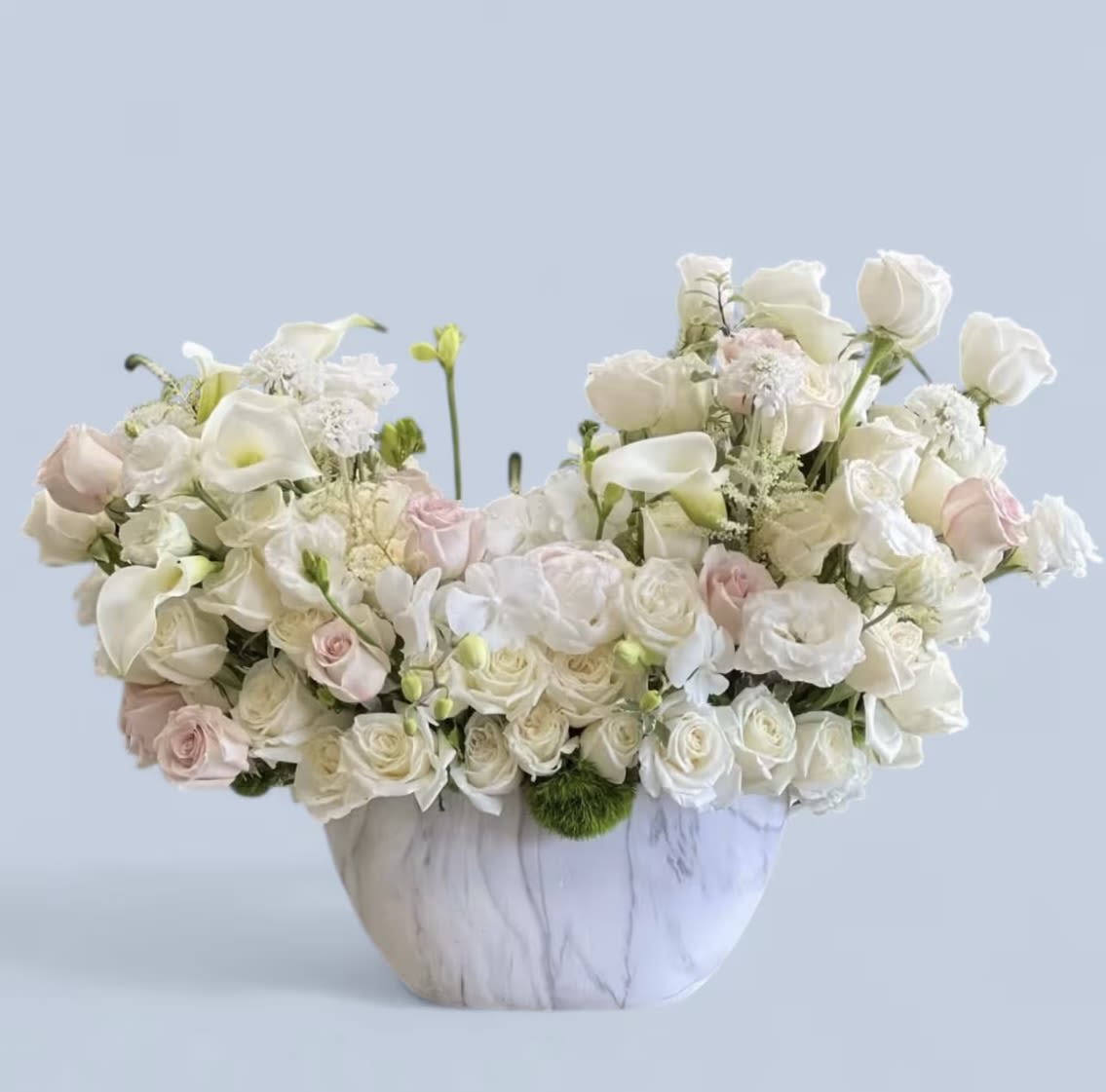 White and blush floral arrangement in a marble-patterned vase