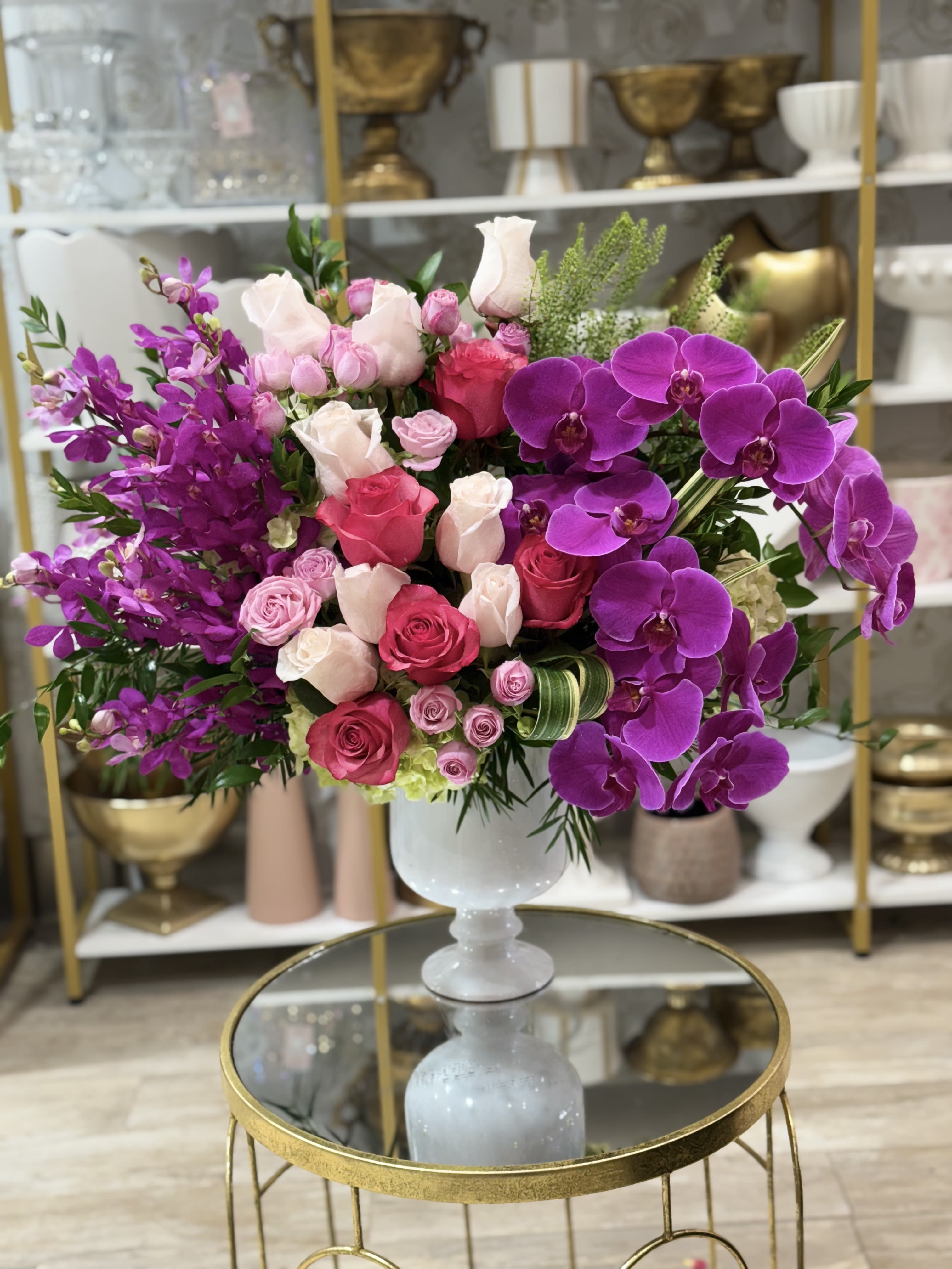 Pink and purple floral arrangement in a white pedestal vase