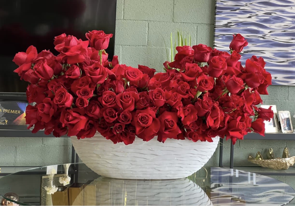 Large arrangement of red roses in a white bowl vase