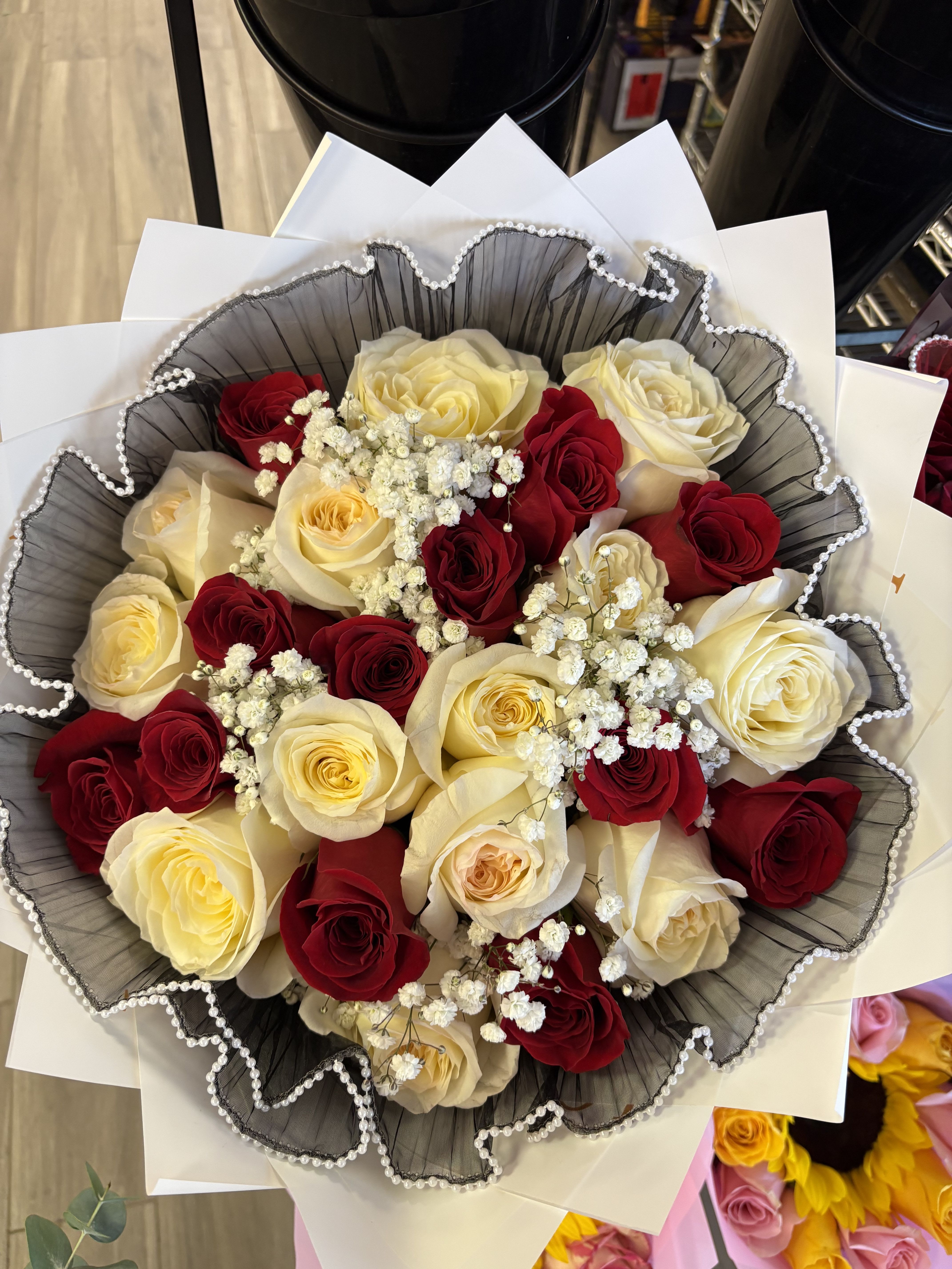 Bouquet of red and cream roses with baby's breath in black and white wrap