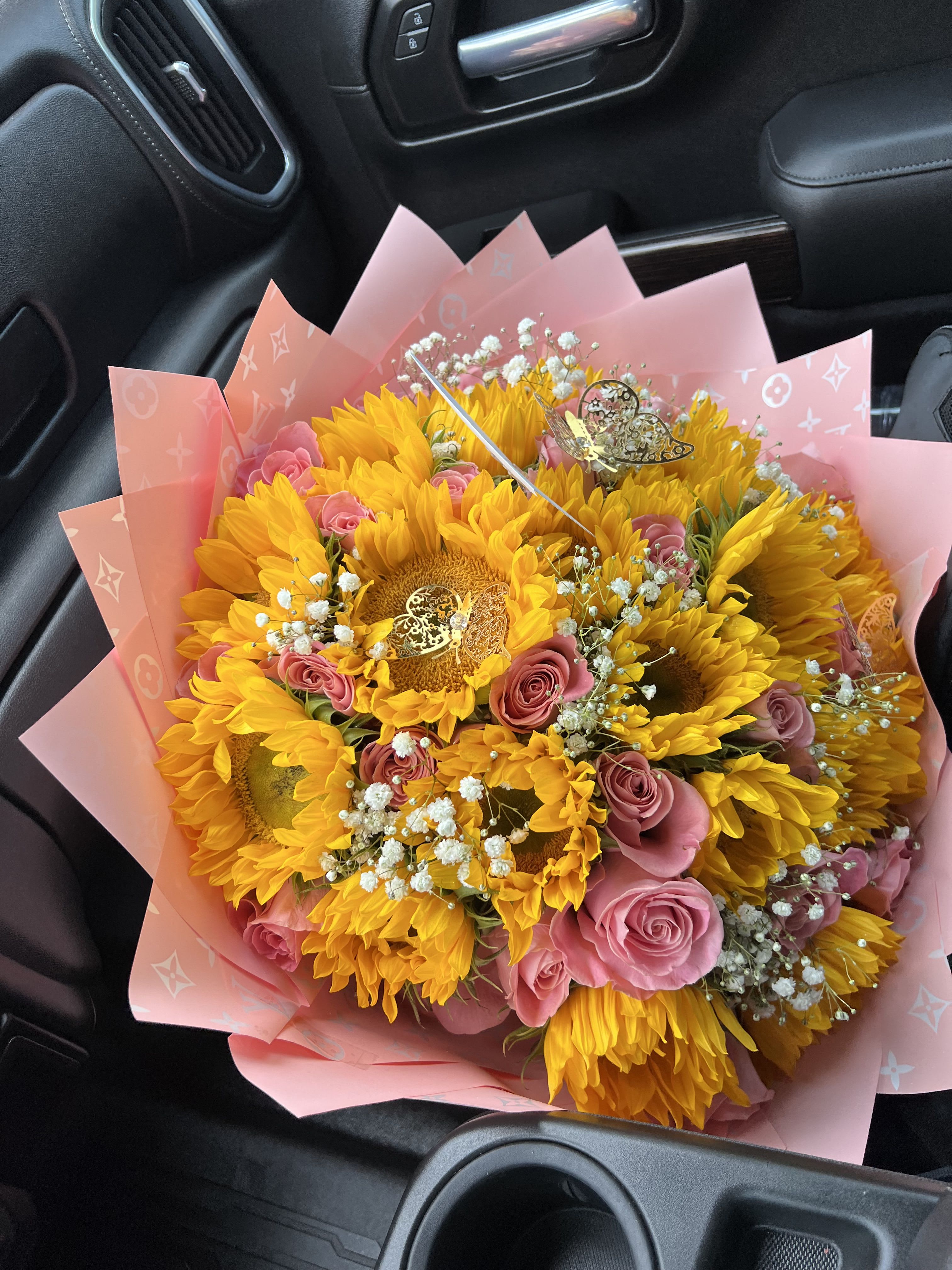 Bouquet of yellow sunflowers and pink roses wrapped in pink paper