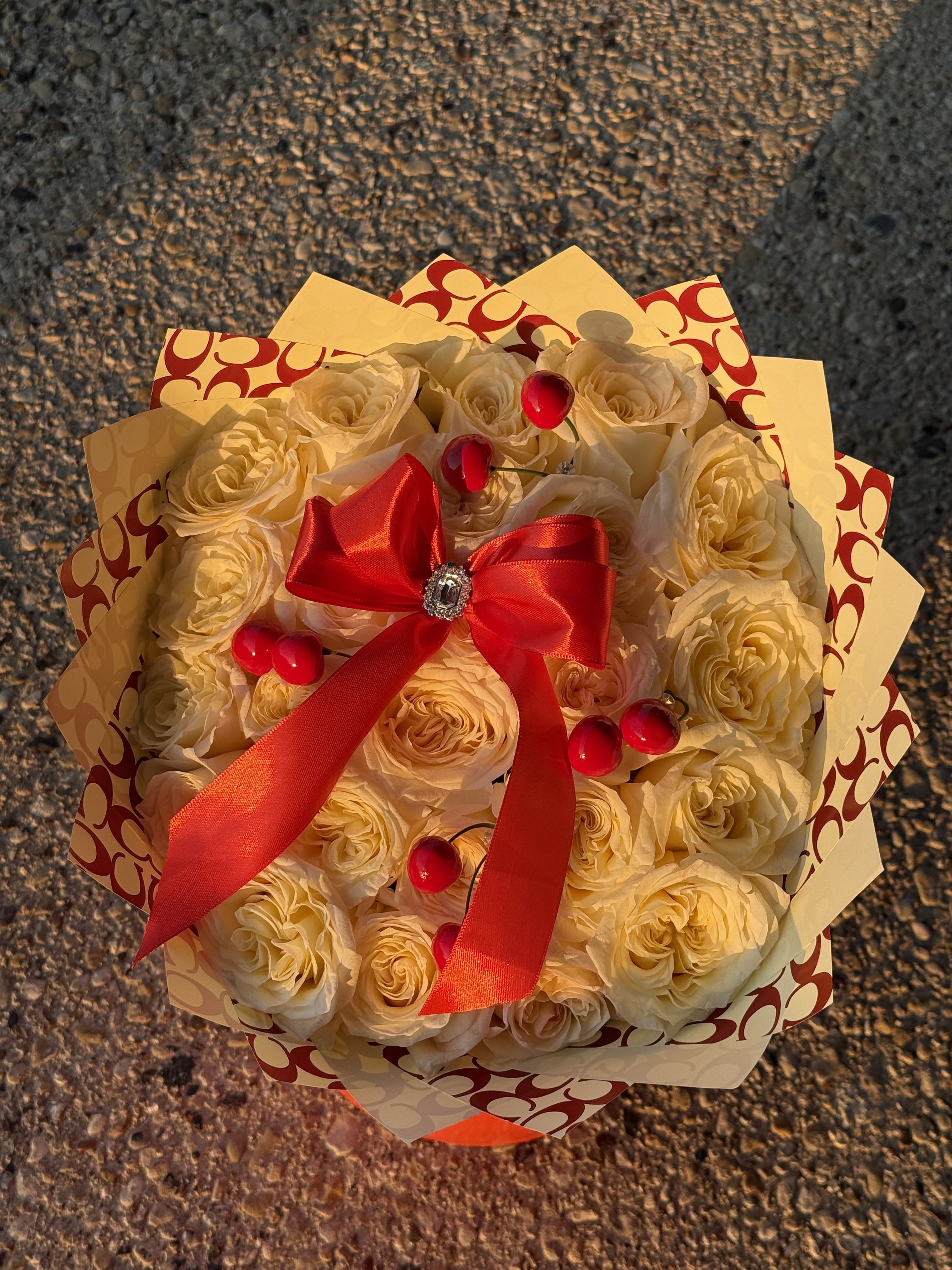 Bouquet of cream roses wrapped with patterned paper and a red ribbon