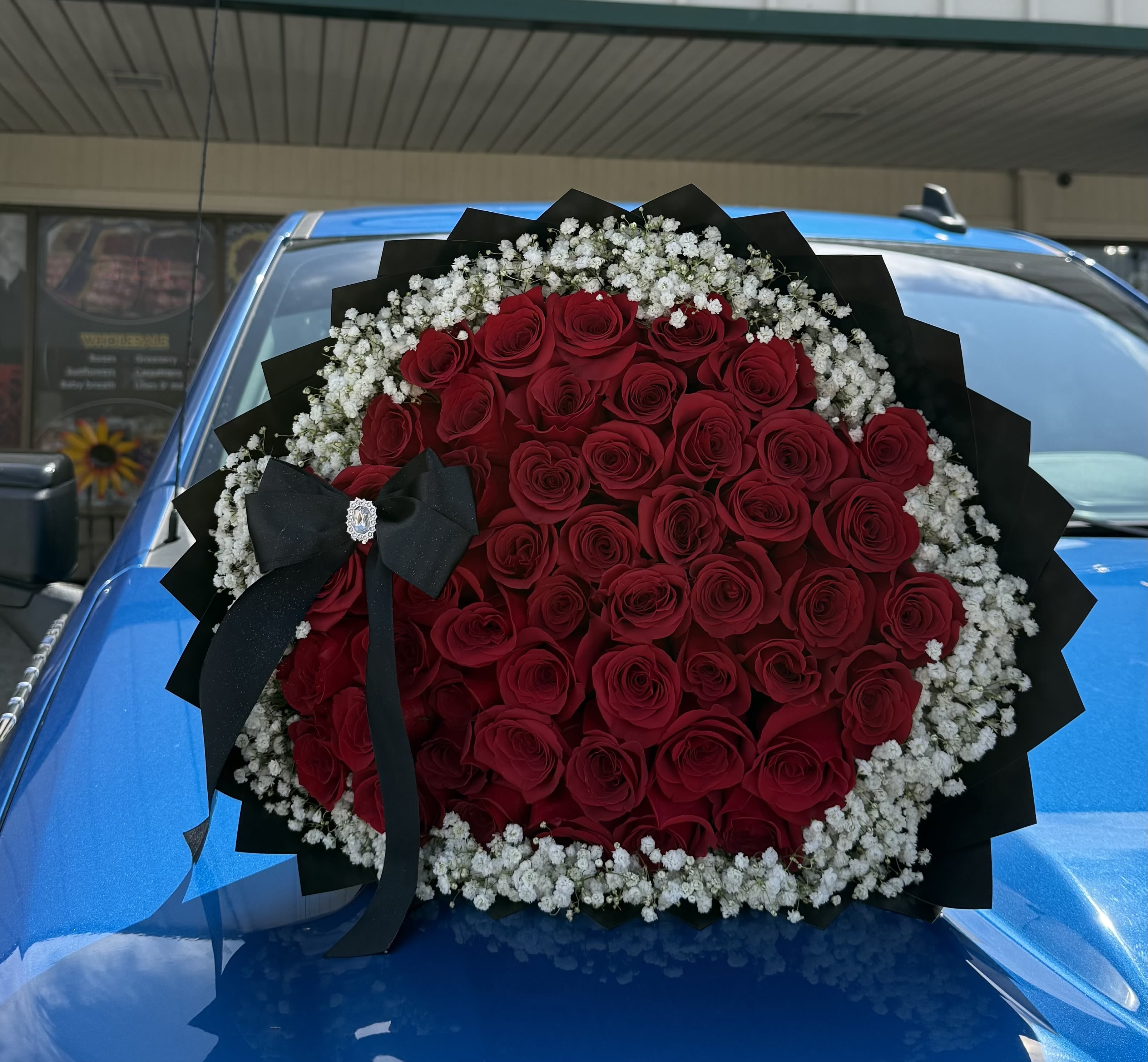 Large bouquet of red roses with white baby's breath and a black ribbon