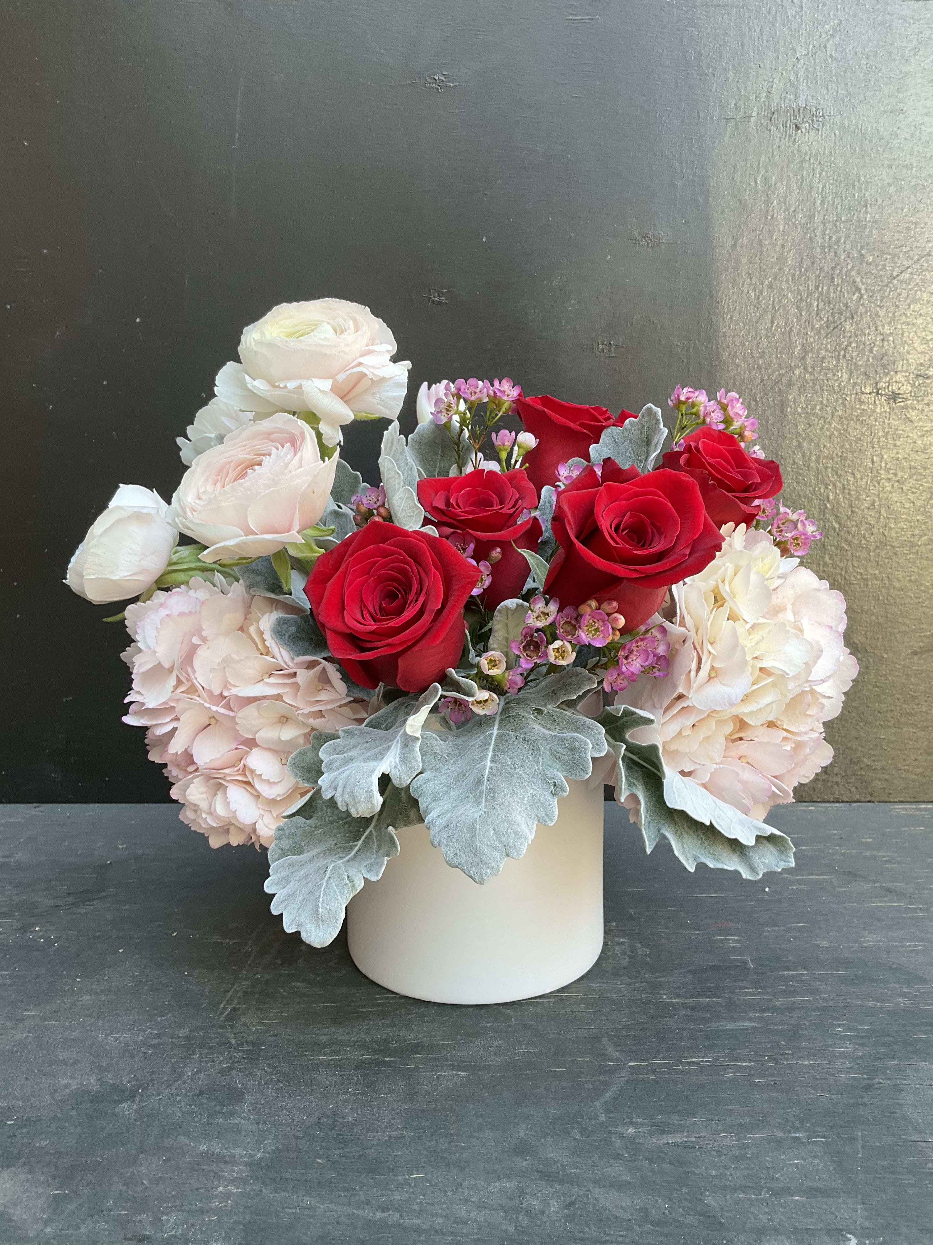 Red and white roses with pale pink blooms in a white vase