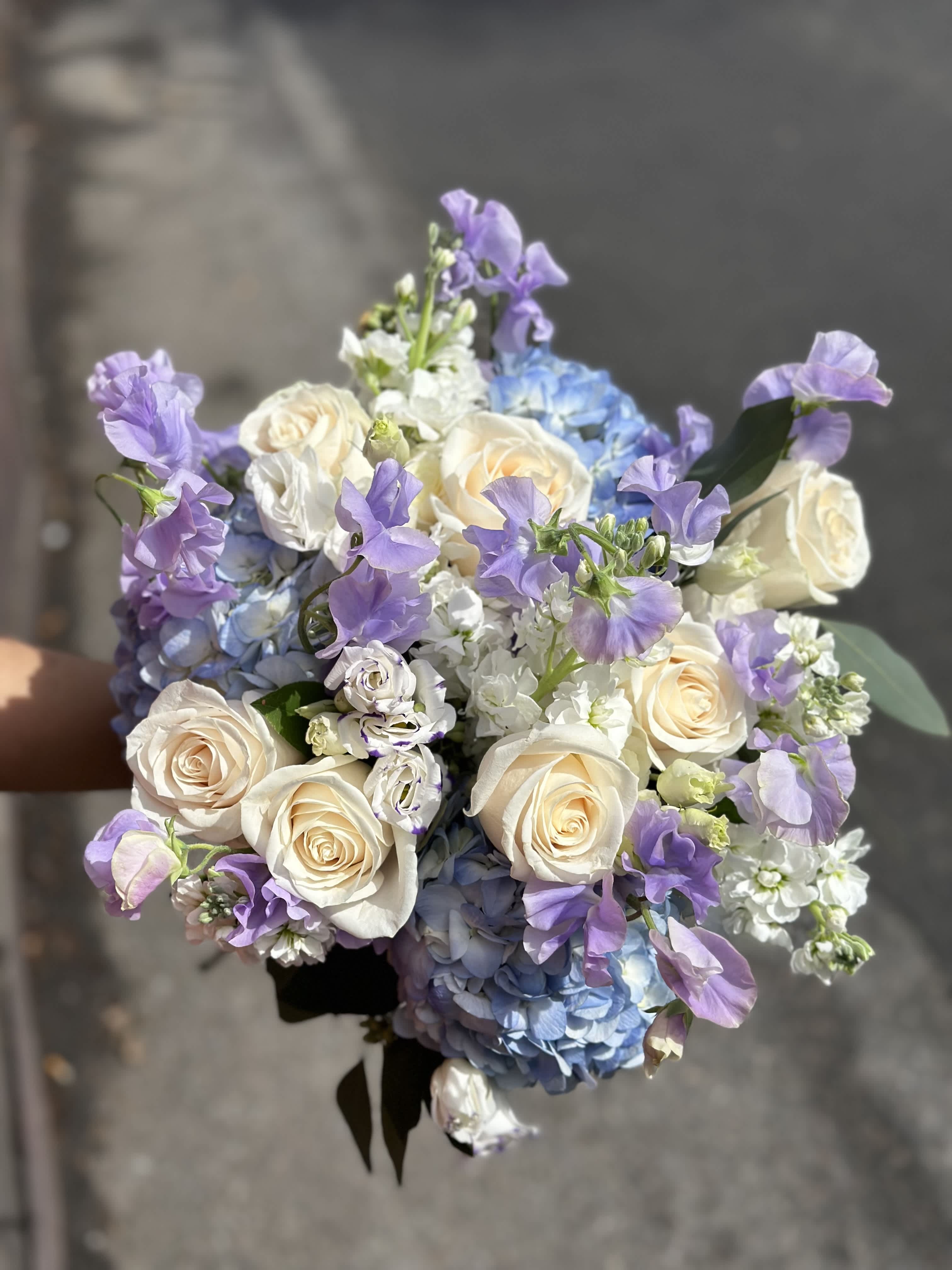 Bouquet of cream roses, blue hydrangeas, and lavender flowers
