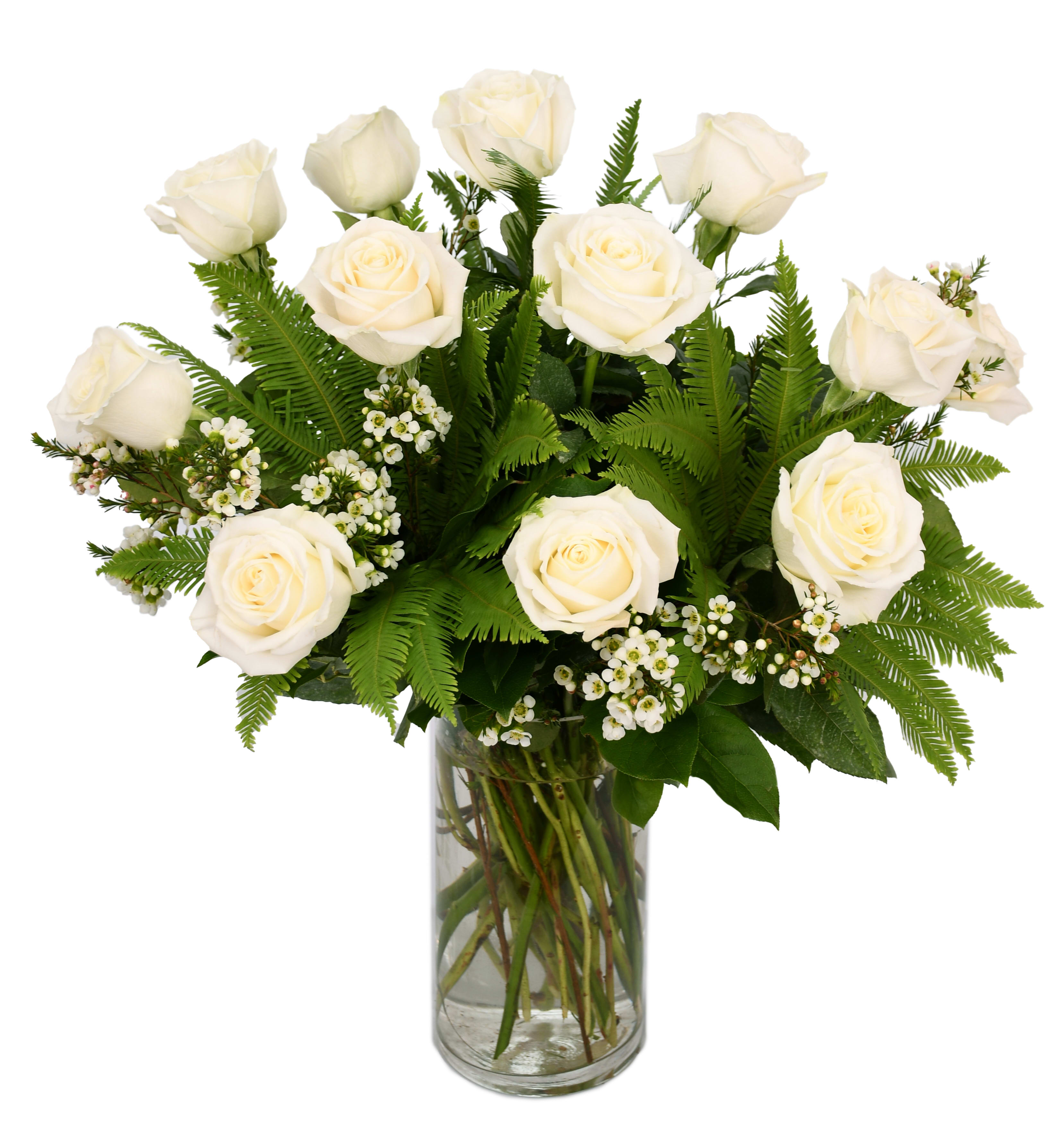 White roses arranged in a clear glass vase with fern foliage