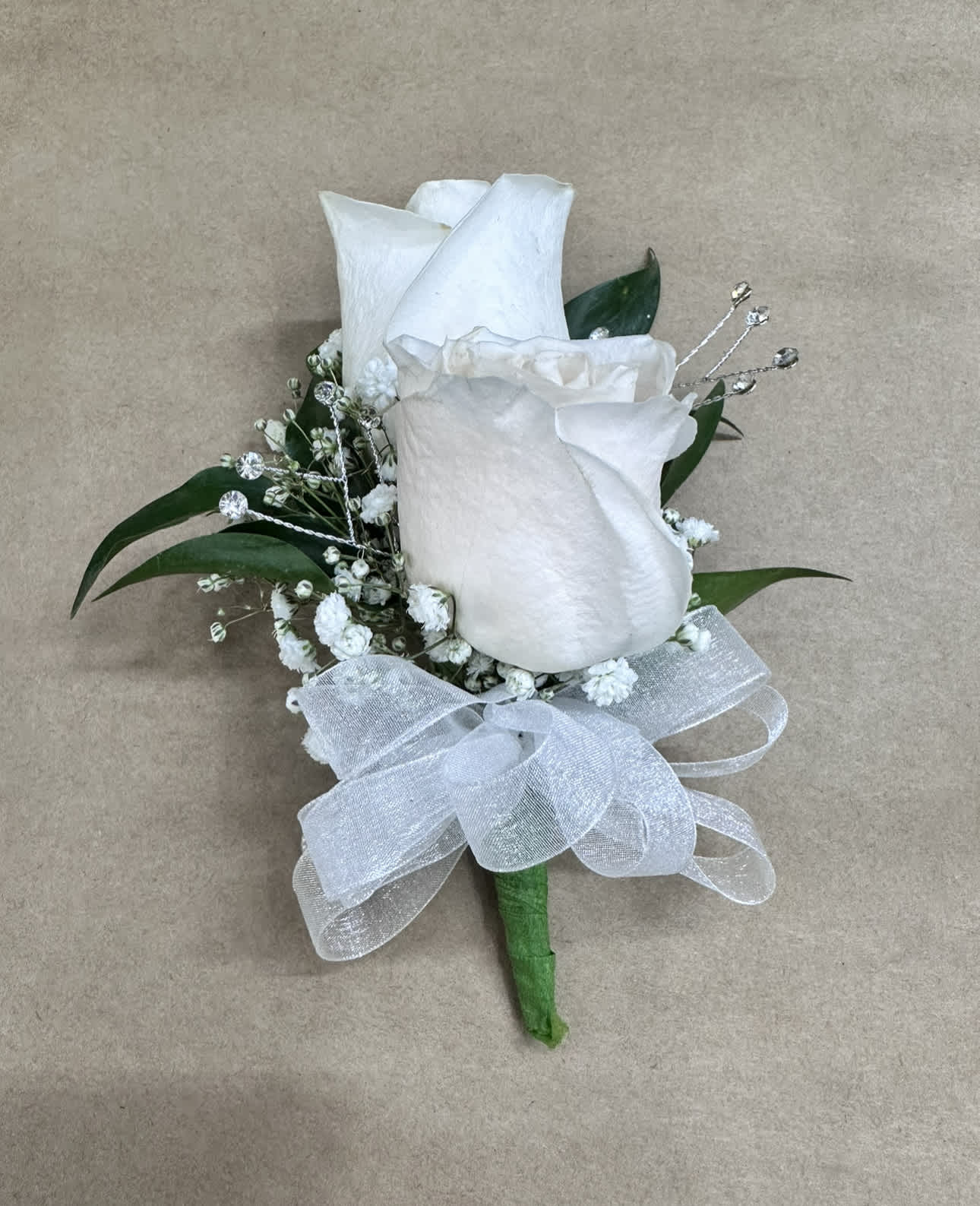 White rose boutonniere with baby's breath, crystal accents, and a sheer white bow.