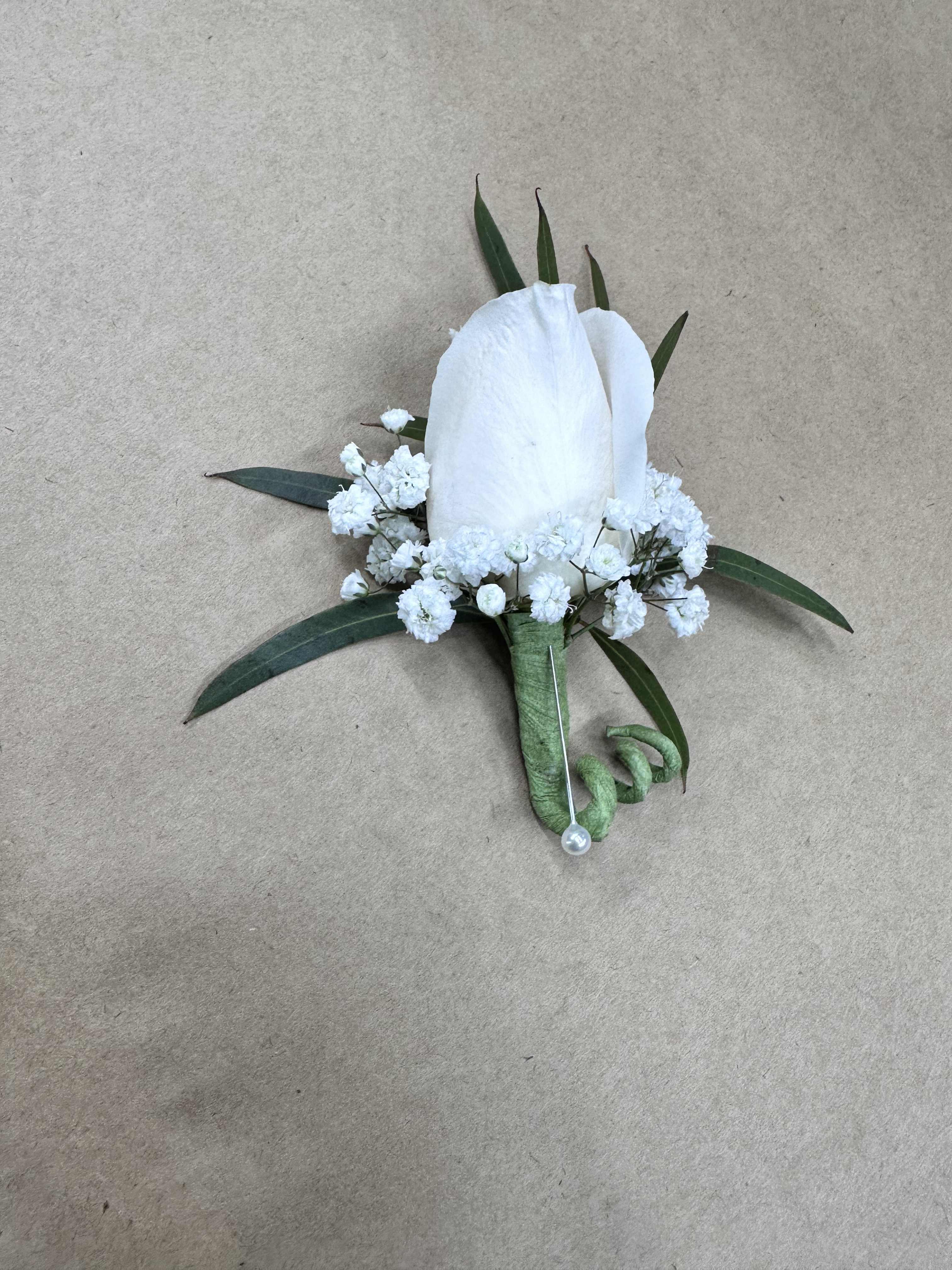 White boutonniere with small white flowers and green leaves