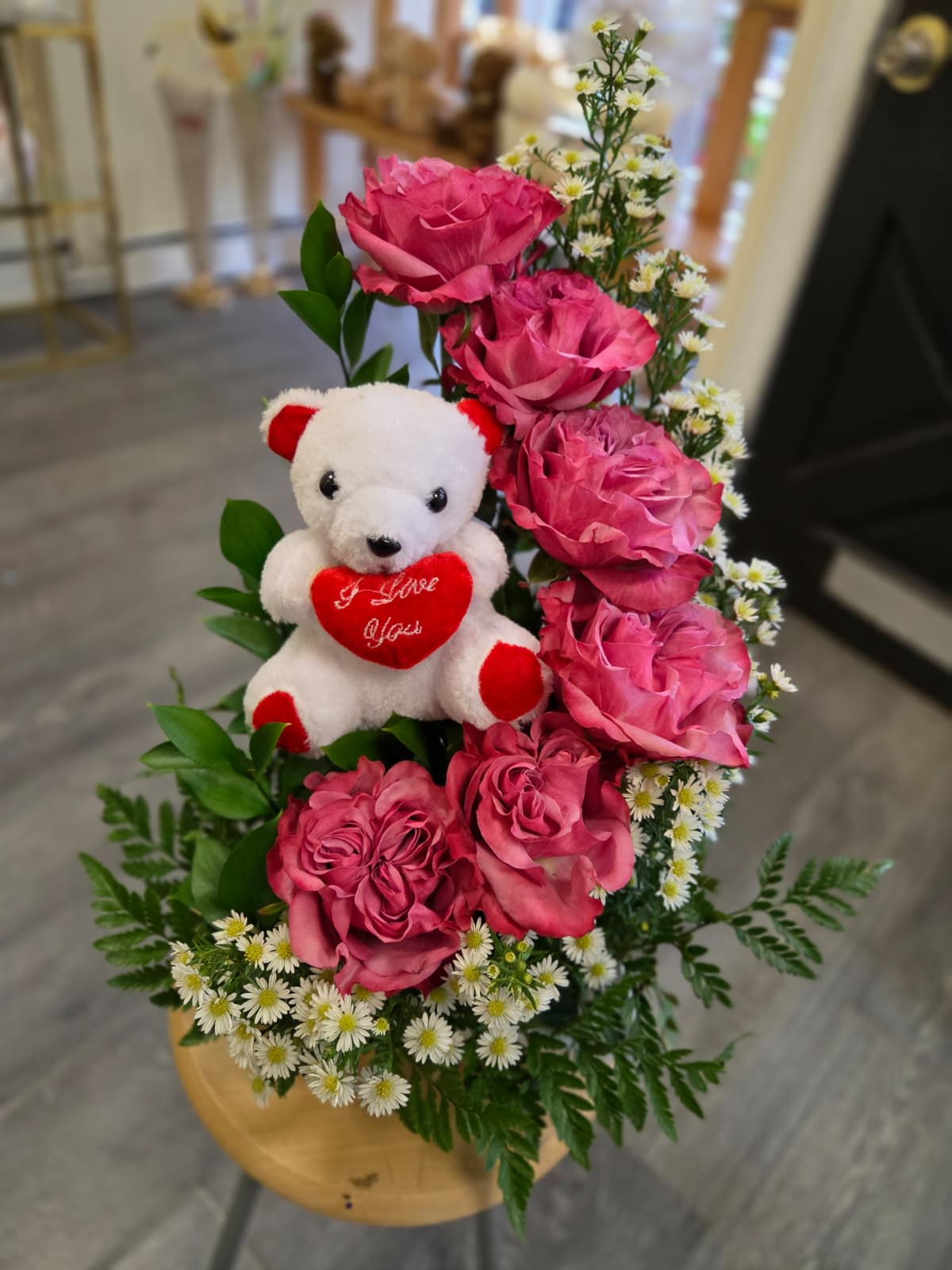 Pink roses with a teddy bear in a wooden container