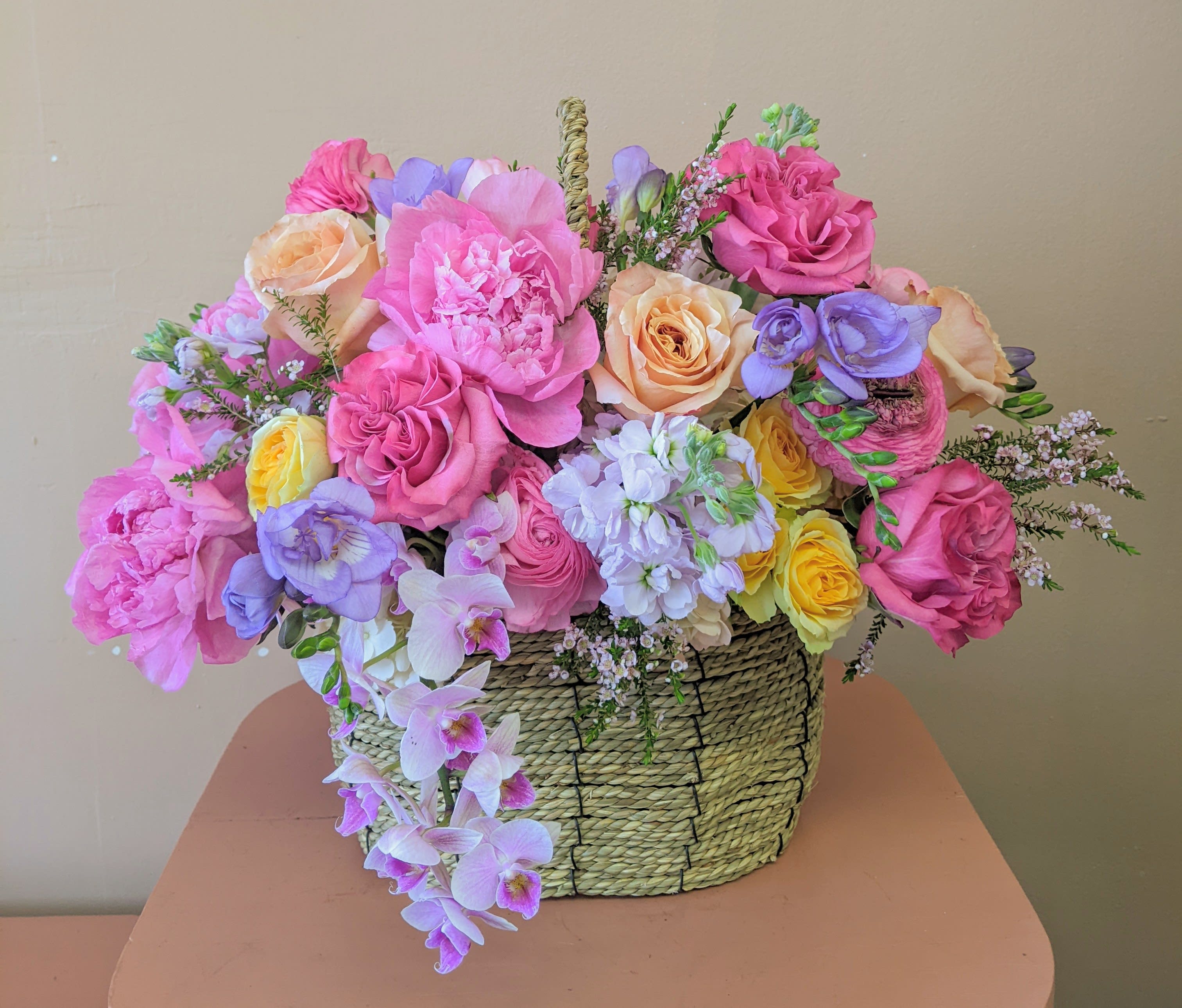 Mixed pink, peach, yellow, and lavender flowers in a woven basket