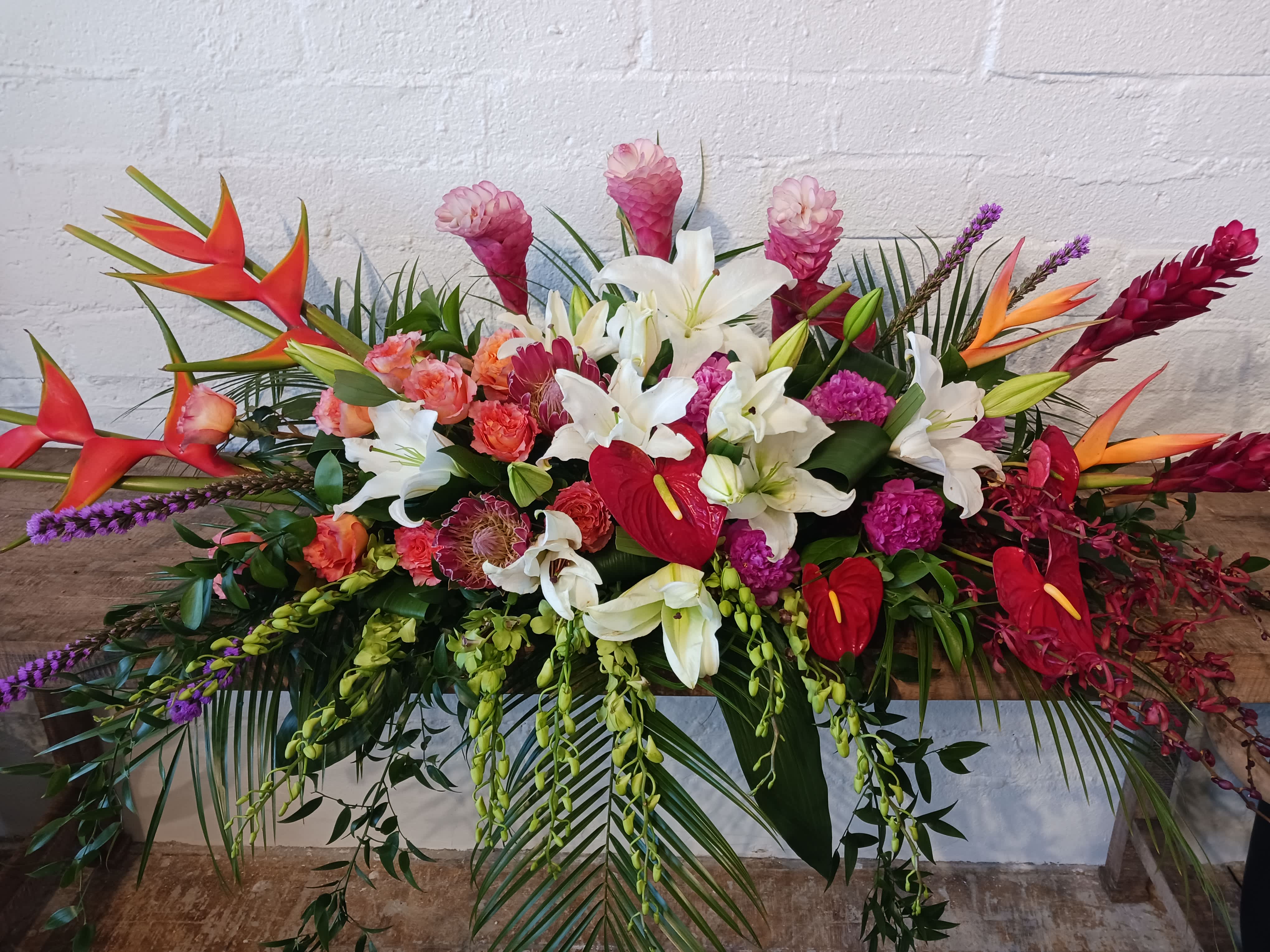 Large tropical floral arrangement with white lilies and red anthuriums