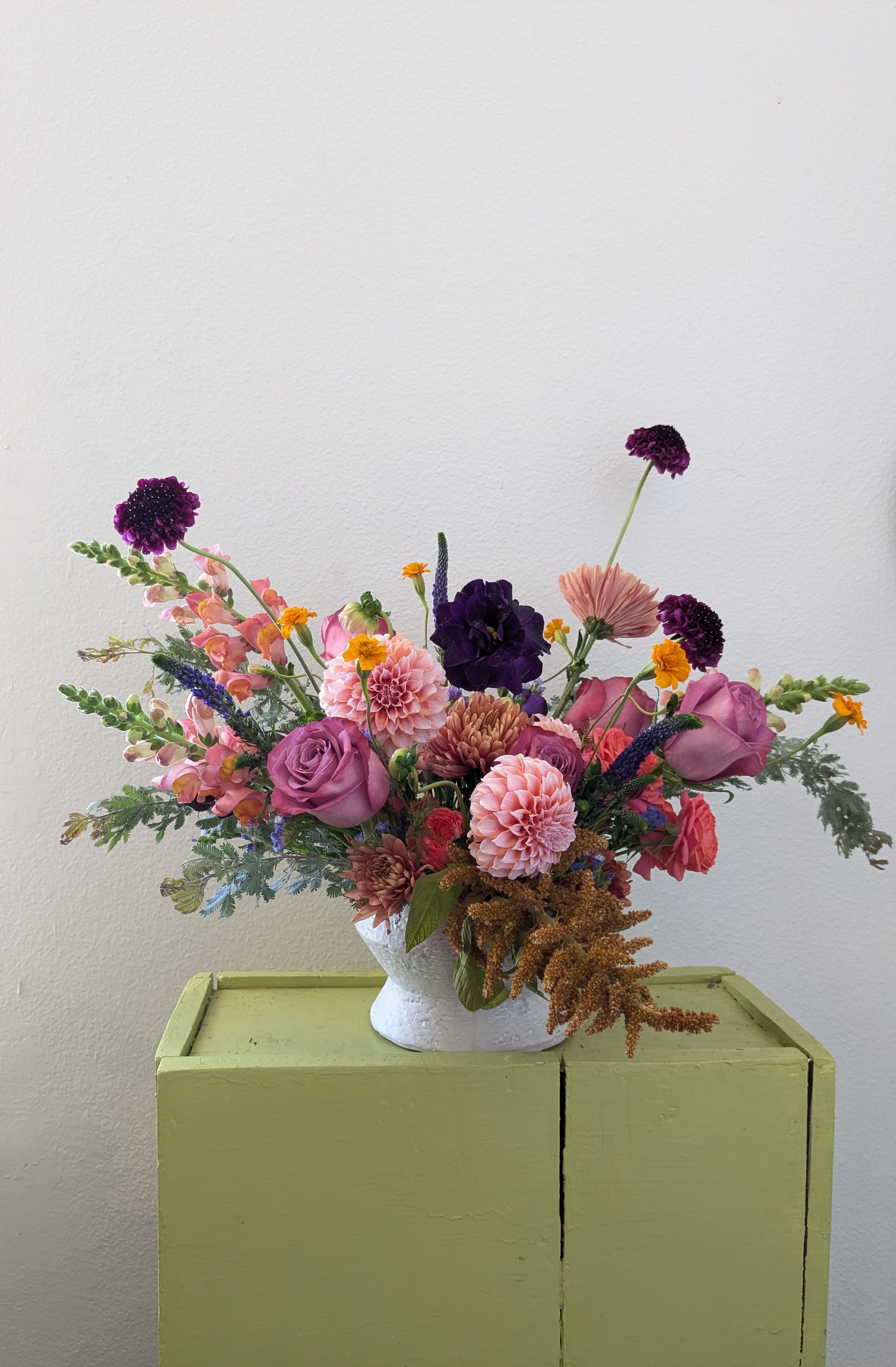 Mixed bouquet in a white vase with pink, purple, and peach flowers