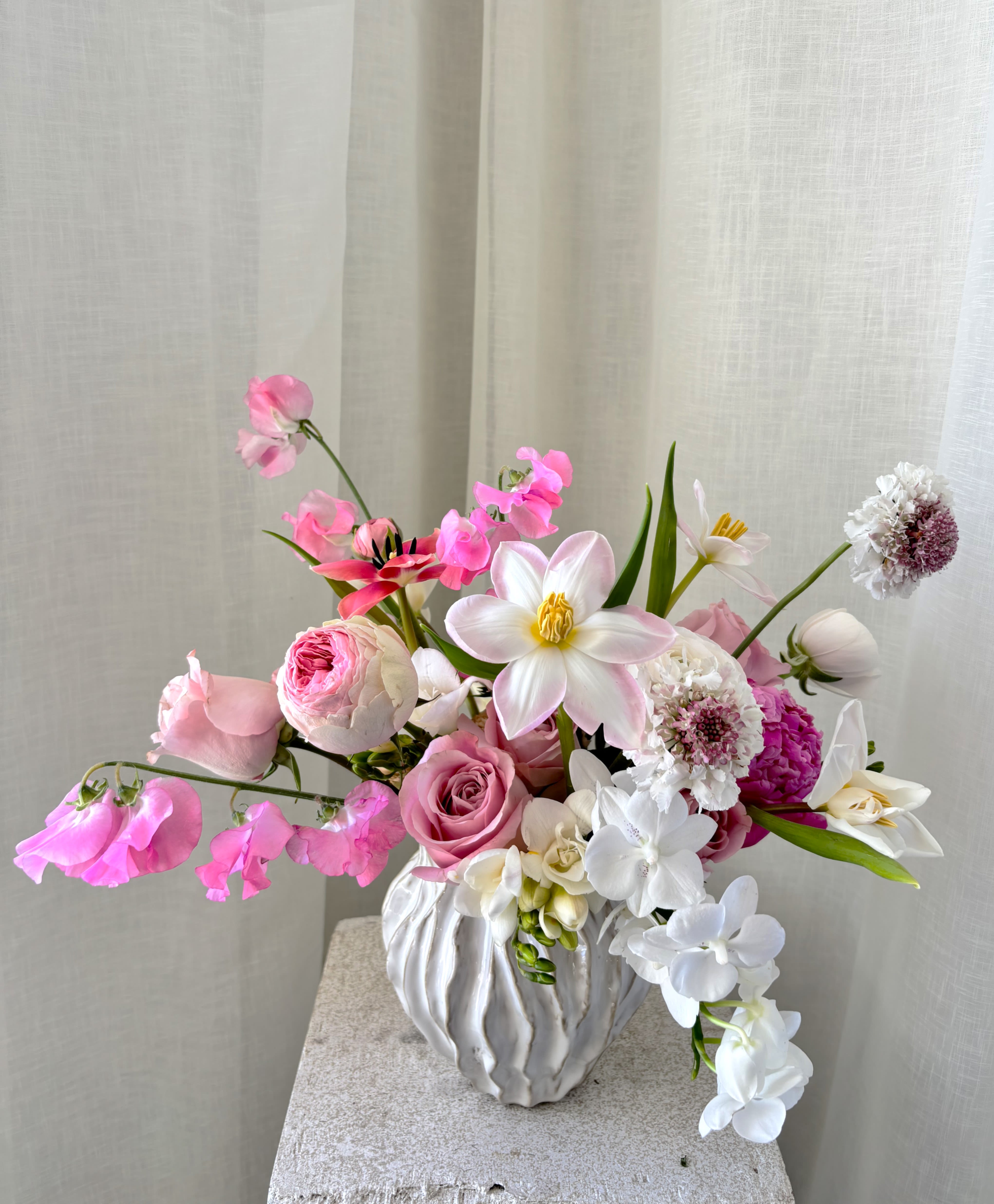 Pink and white floral arrangement in a white textured vase