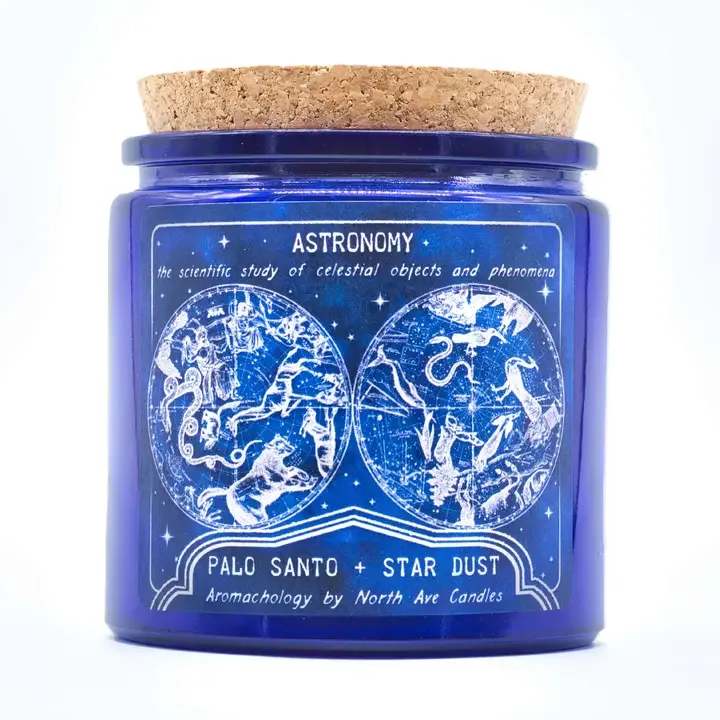 Aromachology Space Candle - Astronomy - the scientific study of celestial objects and phenomena   Reach for the stars!  Palo Santo and Star Dust a harmonious blend of earthy Nag Champa and the sweet, woodsy aroma of Palo Santo  Label art featuring original, in-house artwork inspired by vintage science illustrations showcasing the night sky and its constellation map  Made with coconut-soy wax and poured into a cobalt blue cork-topped apothecary style jar made from recycled glass. Double wicked to ensure an even burn and strong scent throw.  13oz | 80+ burn hours jar dimensions 3.5" diameter 3.5" tall (before cork) finished candle with cork measures approx 4" tall 