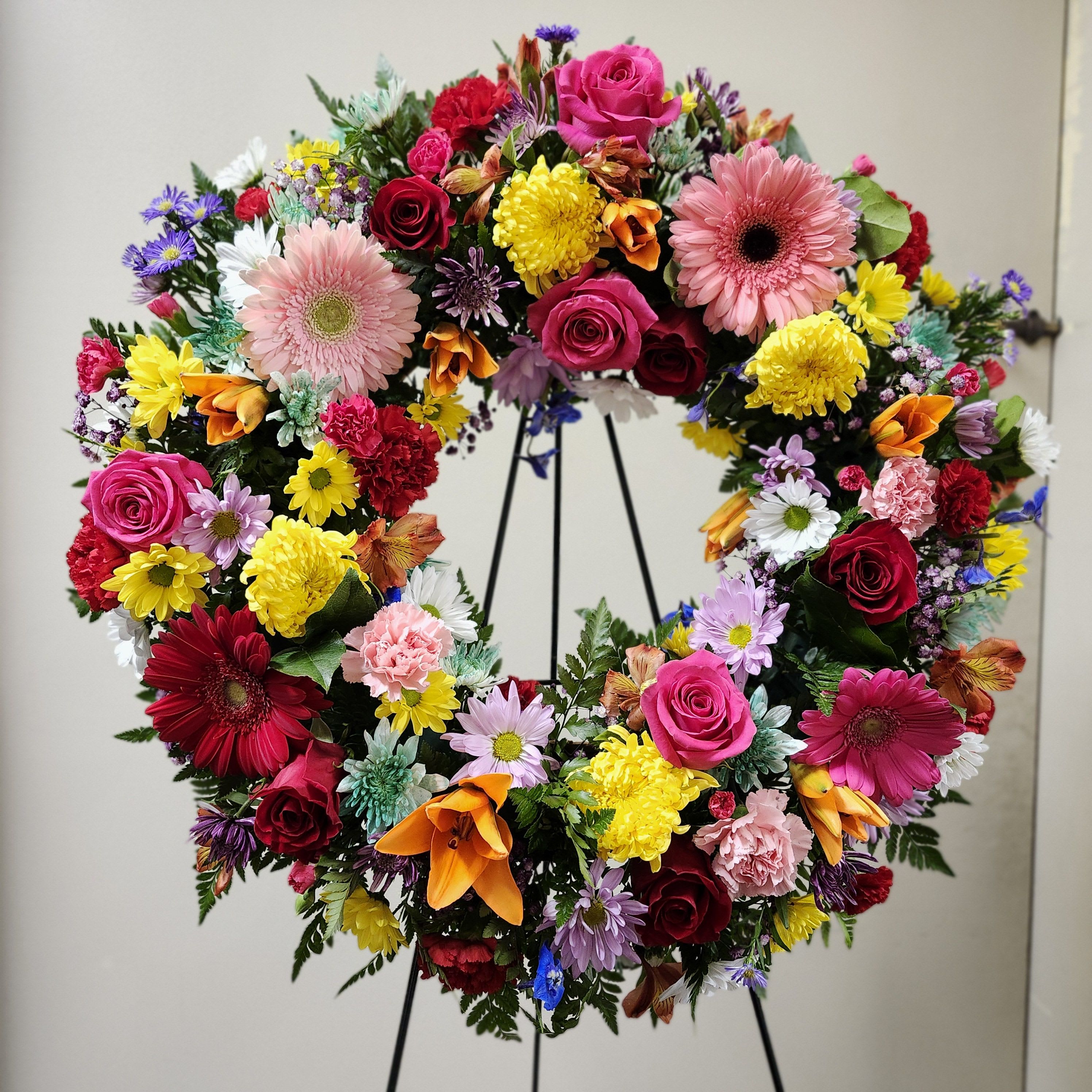 Colorful Life Wreath by Latin Lady Flowers - Colorful Life by Latin Lady Flowers. Remembering those who made our lives brighter and colorful. This sympathy wreath features bright, vibrant, fresh mixed flowers such as roses, lilies, gerbera daisies, carnations, and more. 