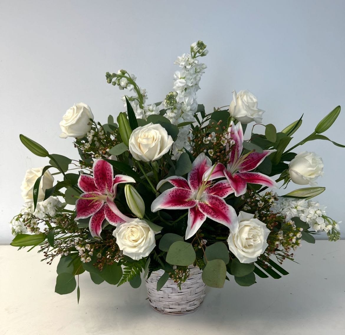 White roses and pink lilies in a white basket vase
