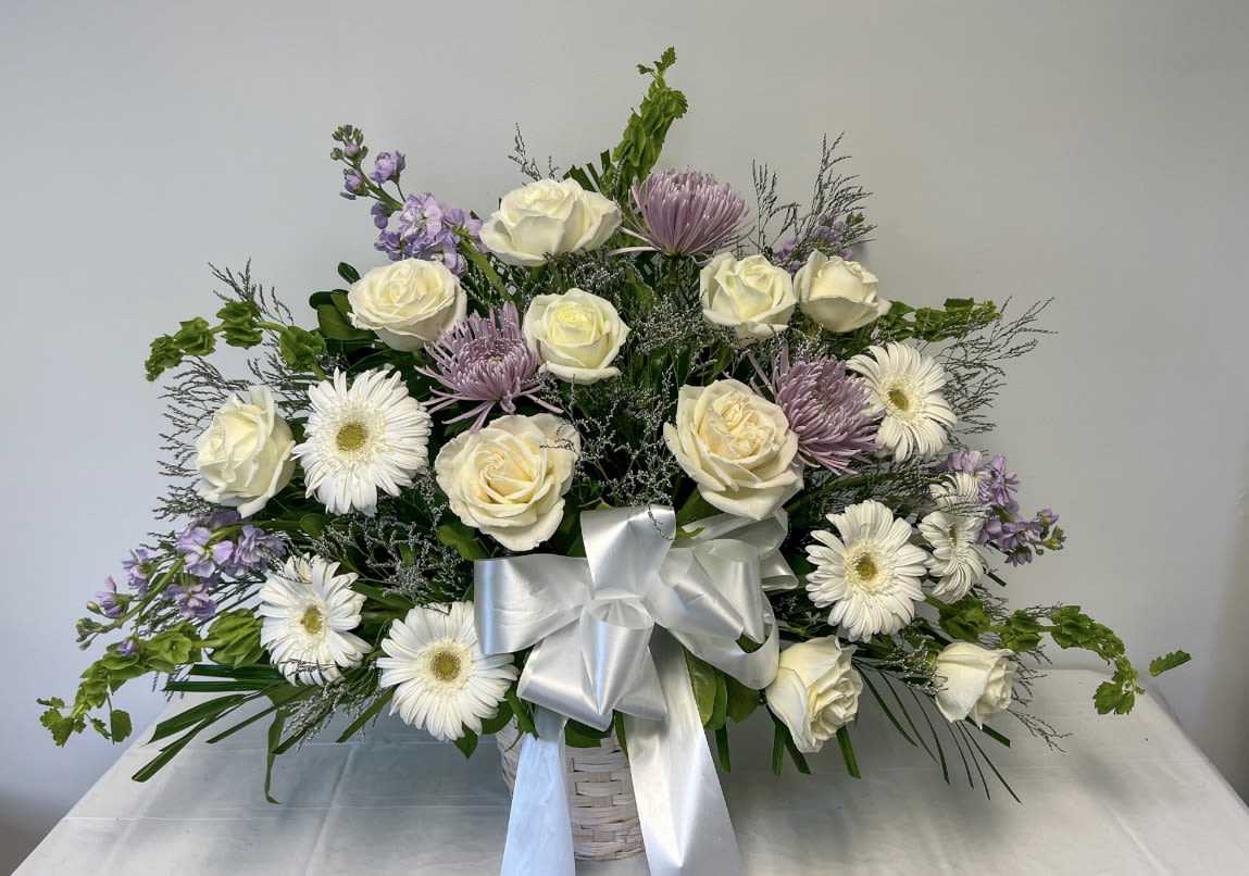 White roses and daisies in a white basket with a silver bow
