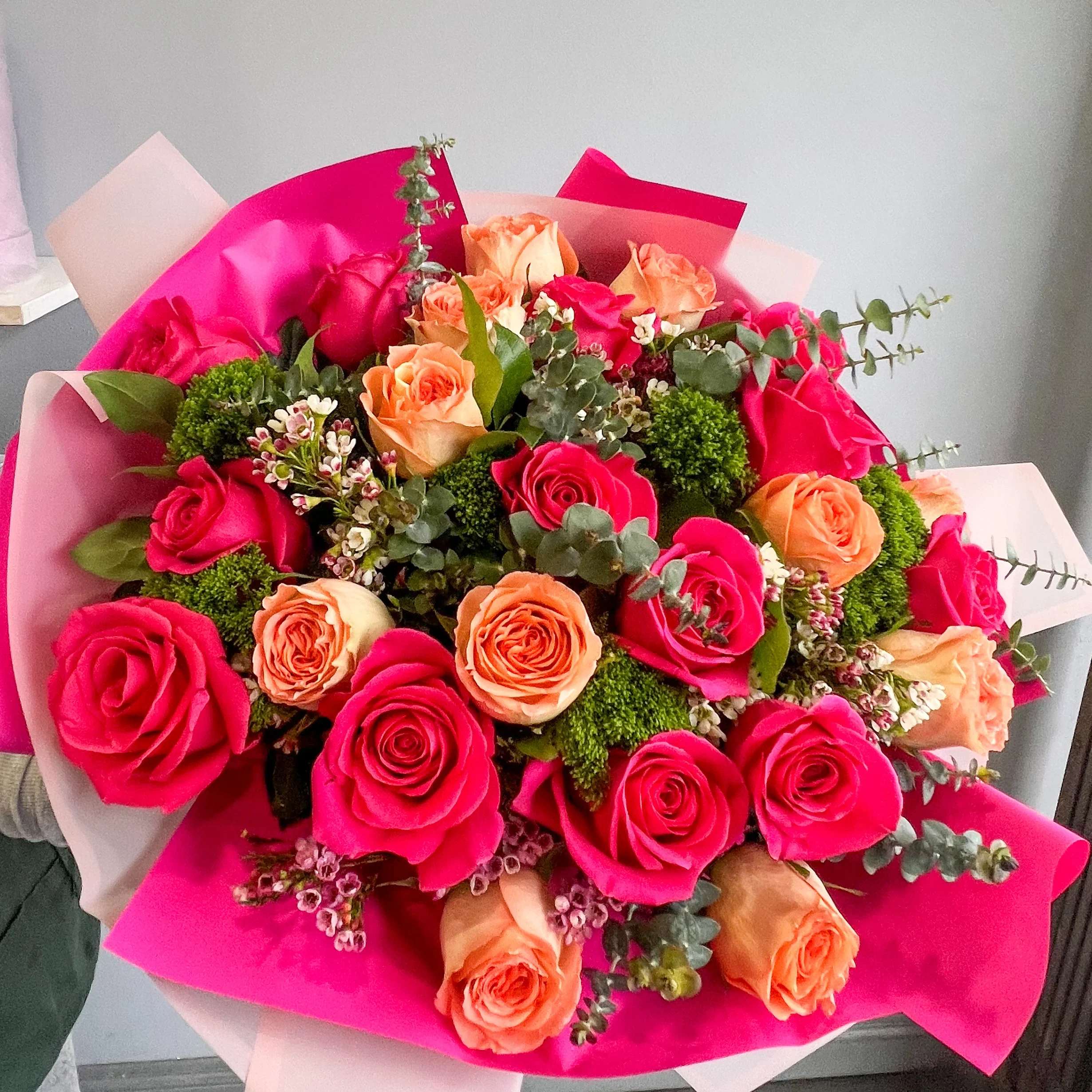 Sunset Sorbet Bouquet - Lush, two-tone roses in hot pink and soft peach create an immediate feeling of warmth and celebration-perfect as a birthday bouquet, anniversary roses, or a romantic Valentine's Day surprise. This rounded, hand-tied arrangement reads like a joyful embrace for the person you're thinking of: she'll feel seen and celebrated the moment the vivid colors and polished presentation arrive.  