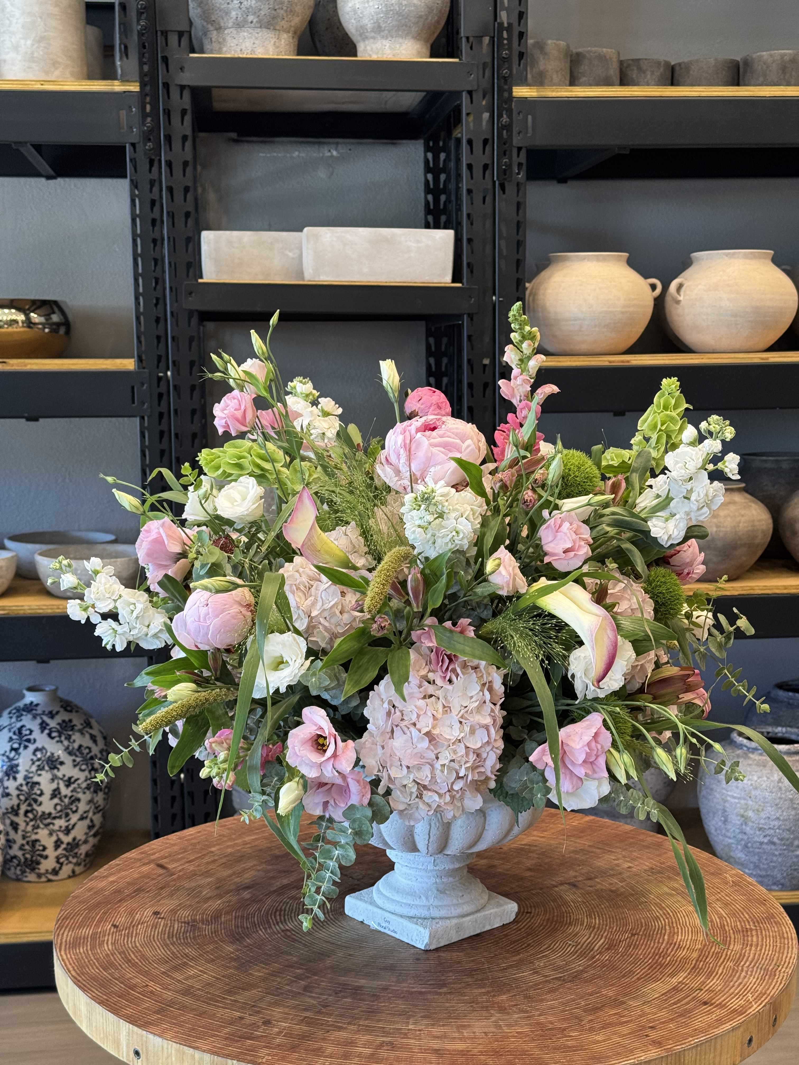 Large pastel floral arrangement in a stone pedestal vase