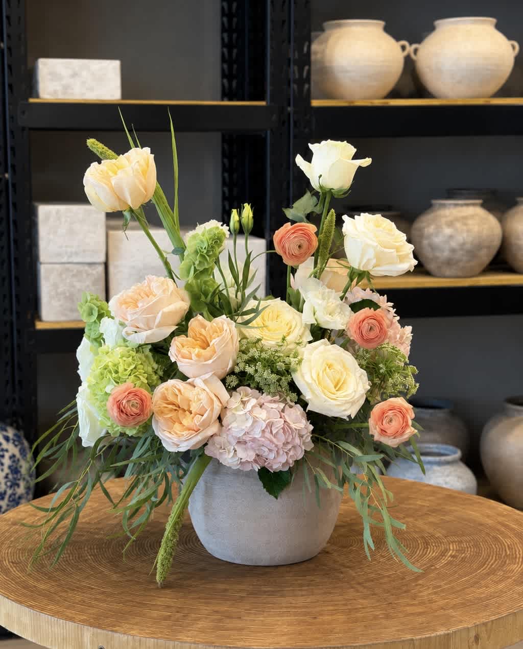 Pastel floral arrangement in a gray vase with roses, hydrangea, and green accents