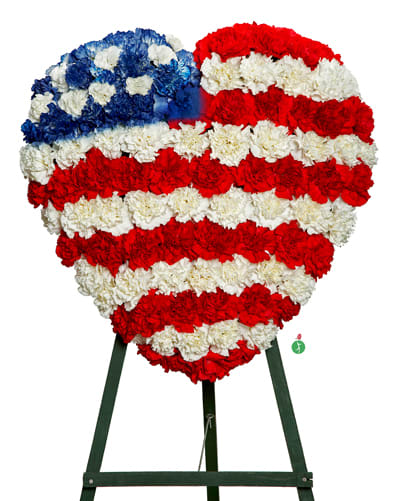 Heart-shaped standing spray of red, white, and blue carnations arranged like the American flag.