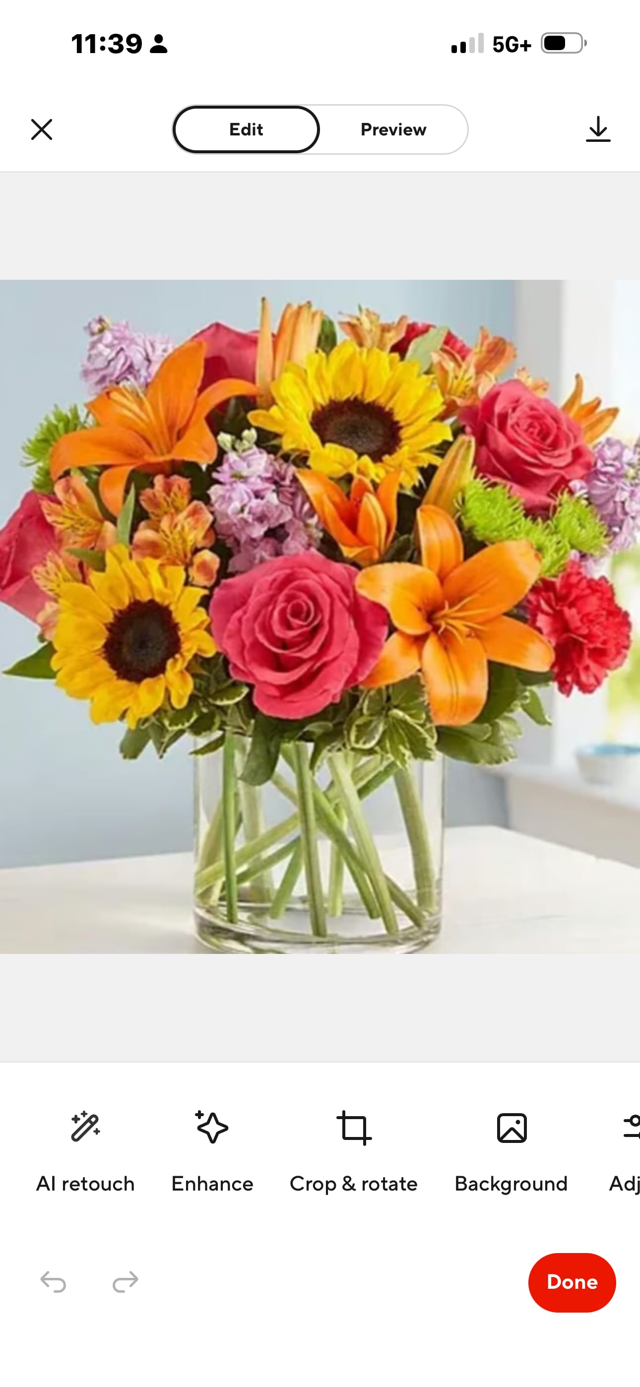 Bright mixed bouquet in a clear glass vase with sunflowers, roses, lilies, and carnations.