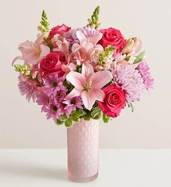 Pink roses and lilies arranged in a tall pink vase