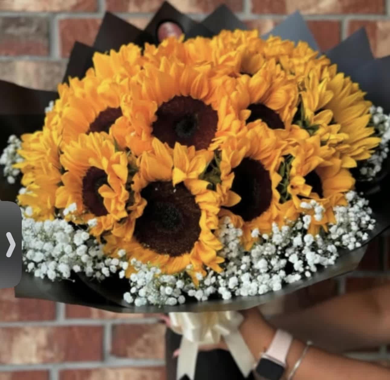 Bouquet of orange sunflowers with white baby's breath in black wrap