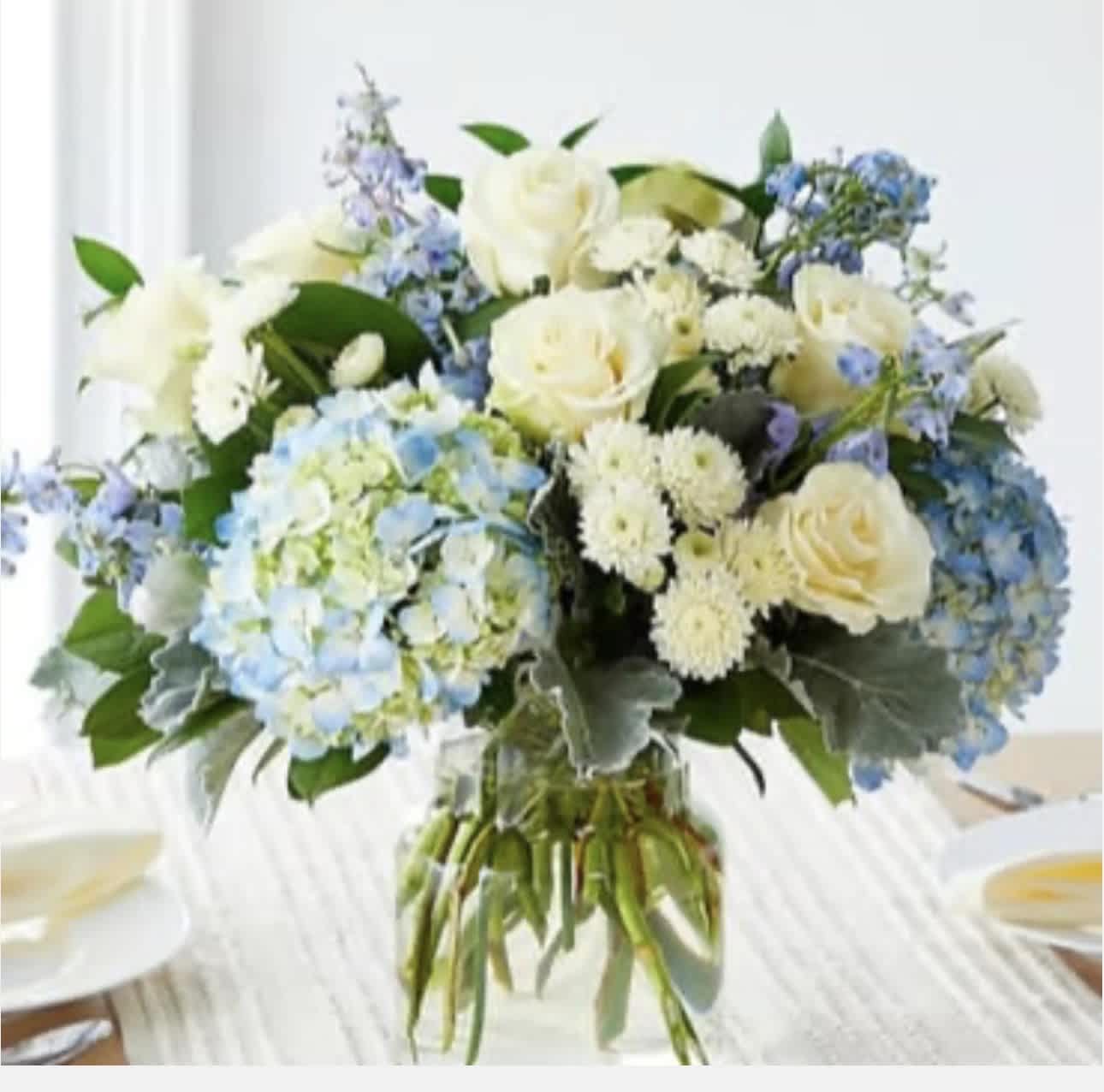 White roses and blue hydrangeas in a glass vase