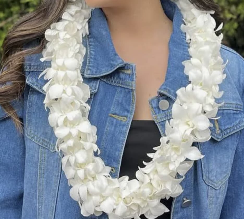 Double White Orchid Lei - A lush, double white orchid lei that reads like celebration around the neck - perfect as a graduation lei or a warm "congratulations" gift for someone stepping into a new chapter. The dense, all-white blossoms create a bright, elegant contrast that keeps the look casual yet special for ceremonies, parties, or a sunny welcome home. No vase or container is needed - it's ready to put on and wear the moment it's delivered.  Ideal for graduates, honored guests, or anyone you want to make feel recognized, this lei sends a clear message of celebration and warmth. Handle gently and store flat or hung when not in use to preserve the shape of the blossoms; ordering is straightforward for pickup or delivery so your recipient can enjoy the moment without fuss.