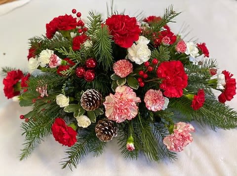Red and pink carnations with pinecones in a holiday arrangement