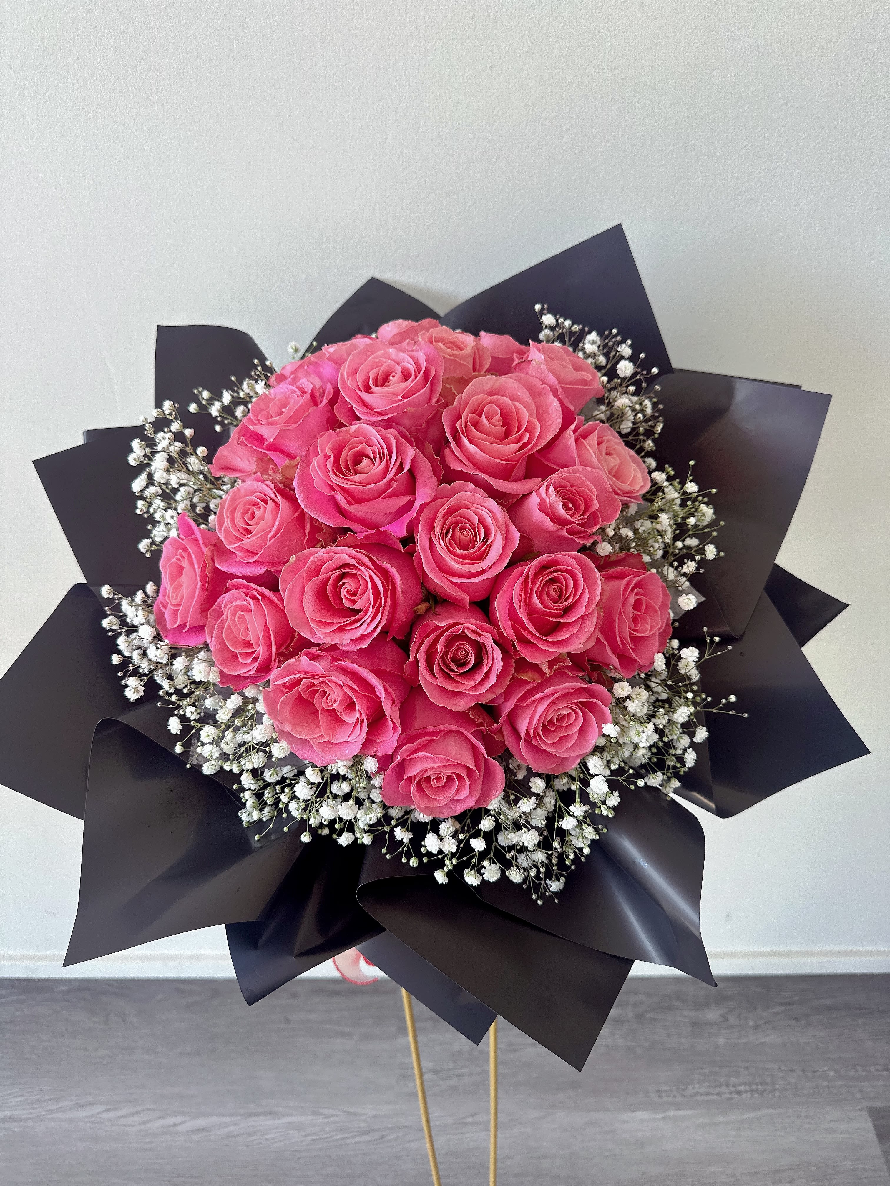 Bouquet of pink roses with white baby's breath in black wrap