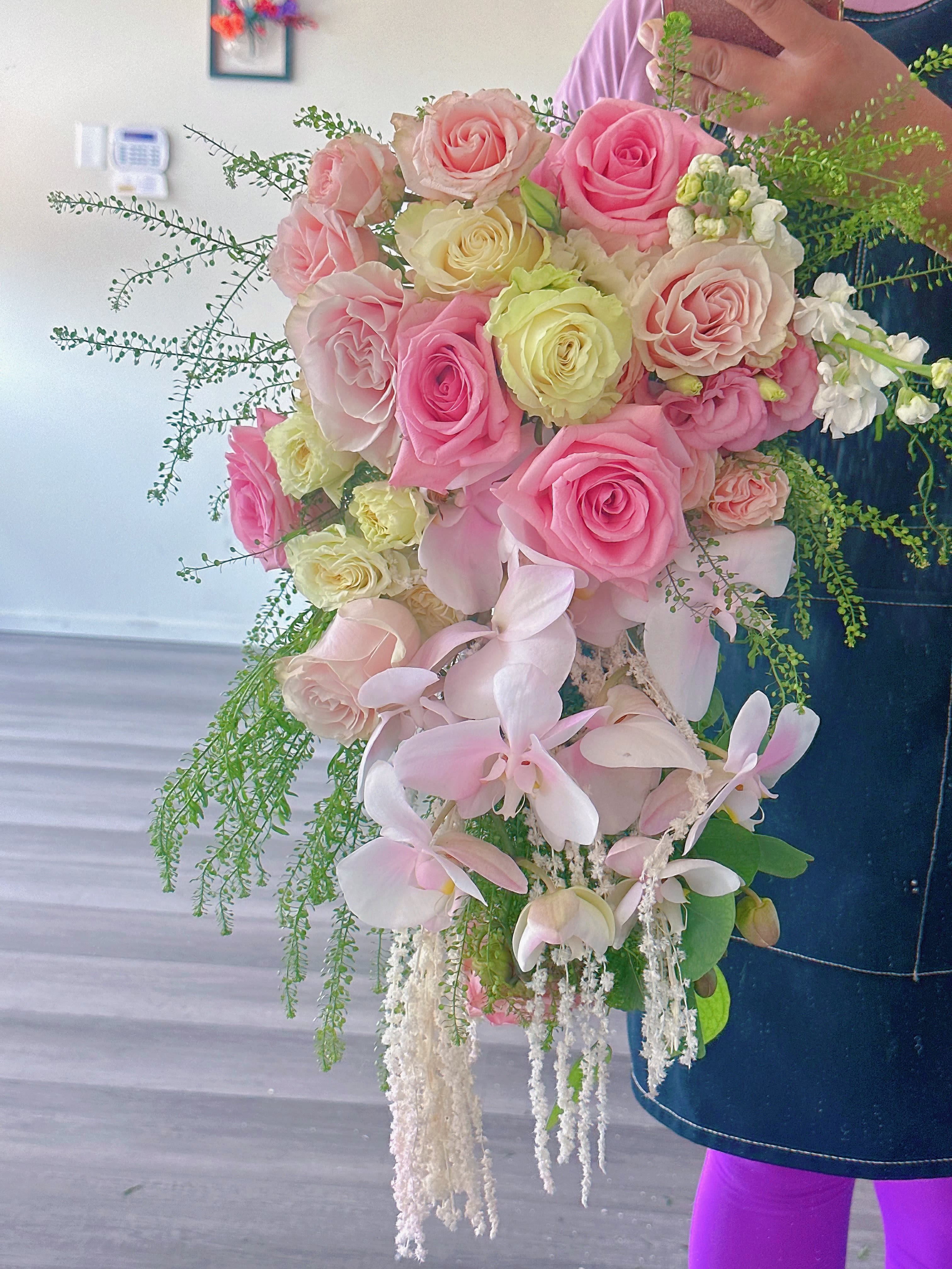 Handheld bouquet of pink and cream roses with pale orchids