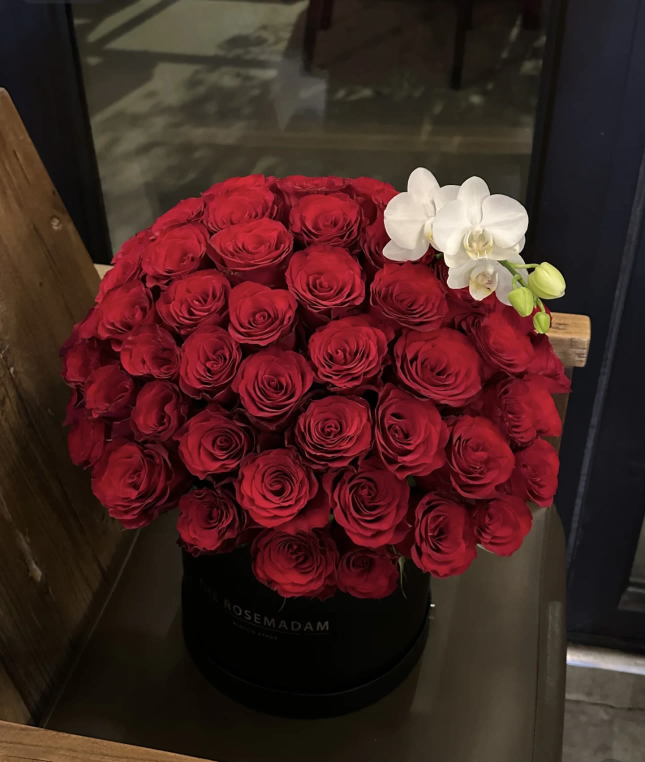 Large red rose arrangement with white orchids in a black hat box