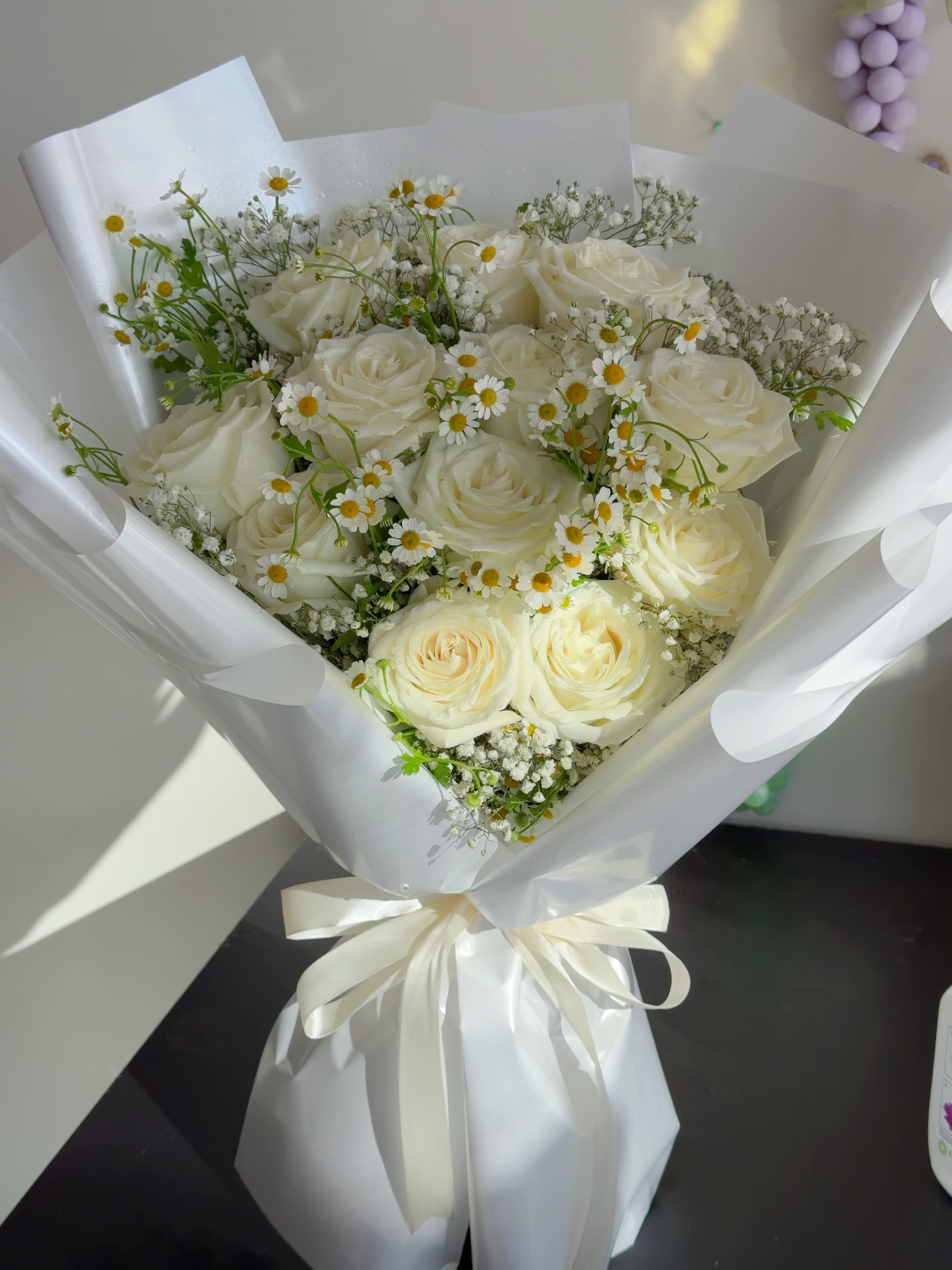 Bouquet of white roses and small daisy flowers wrapped in white paper