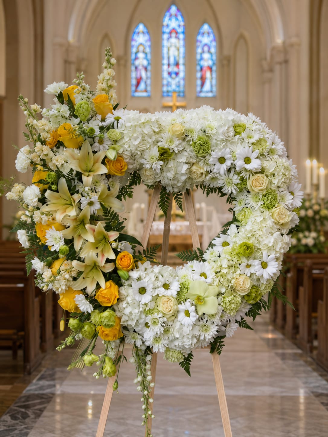 Heart-shaped floral wreath on an easel with white and yellow flowers