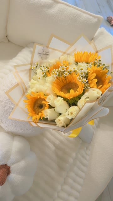Bouquet of sunflowers and white roses wrapped in cream paper