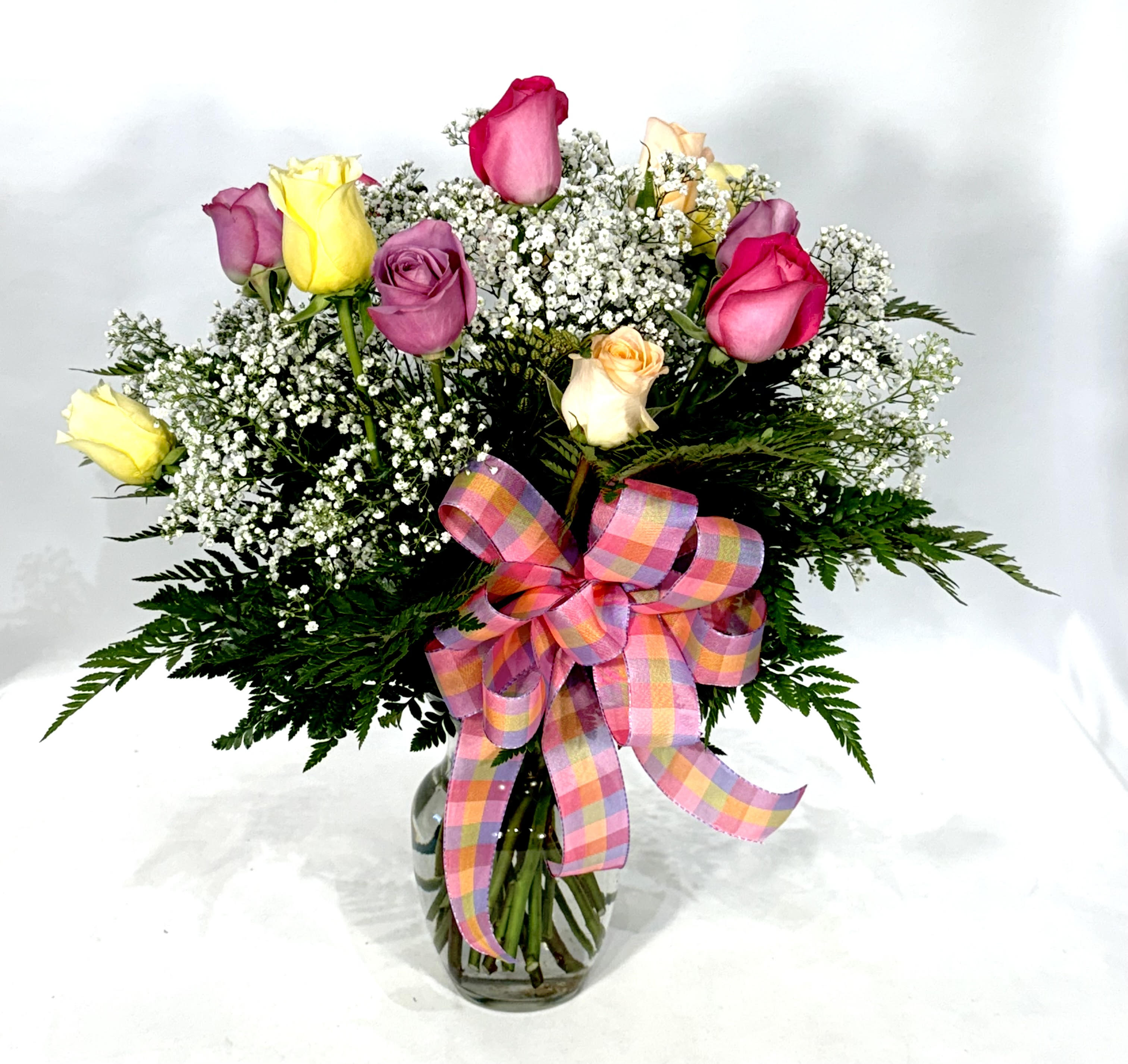 Bouquet of multicolored roses with baby's breath in a glass vase