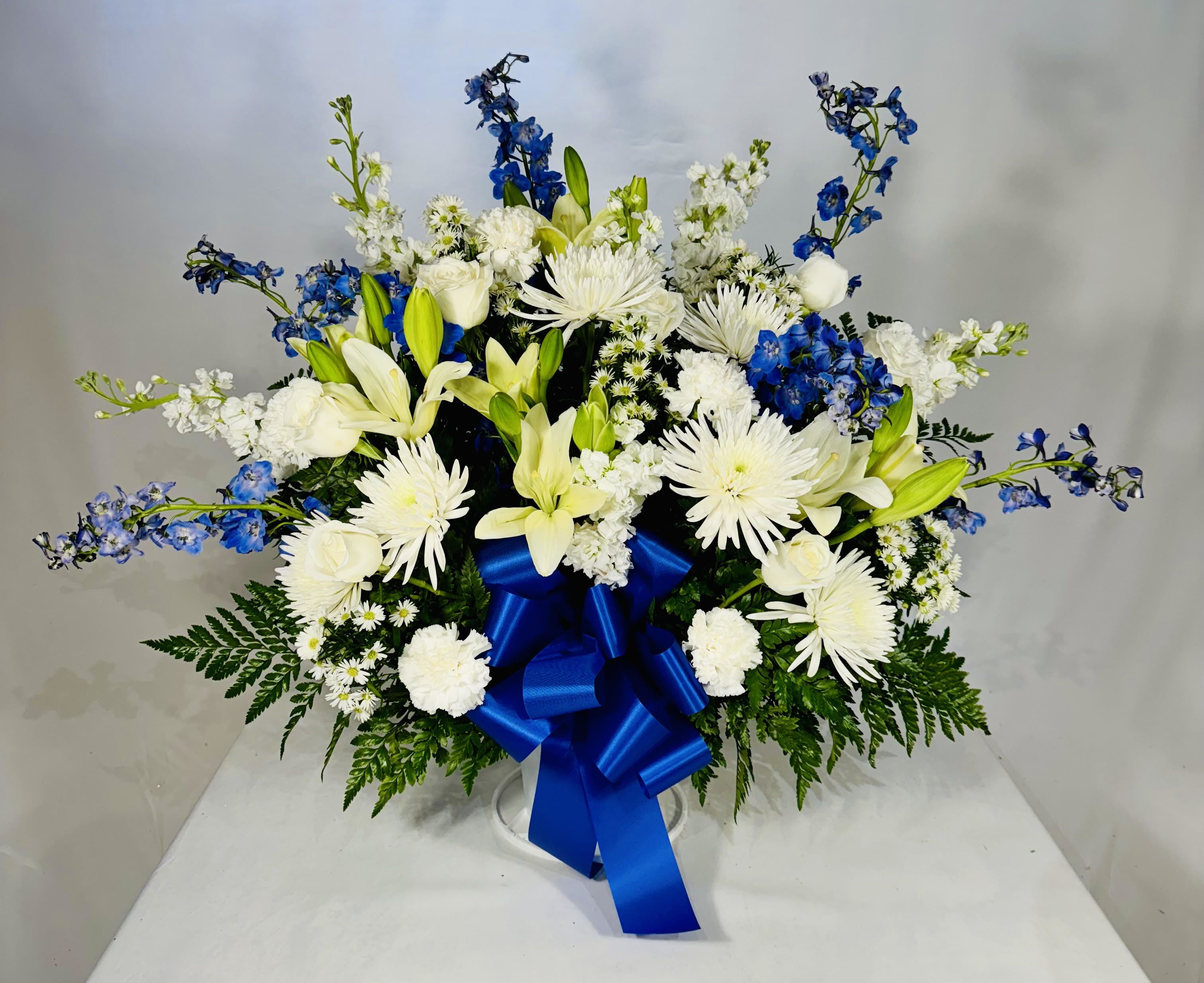 White and blue floral arrangement with a large blue ribbon
