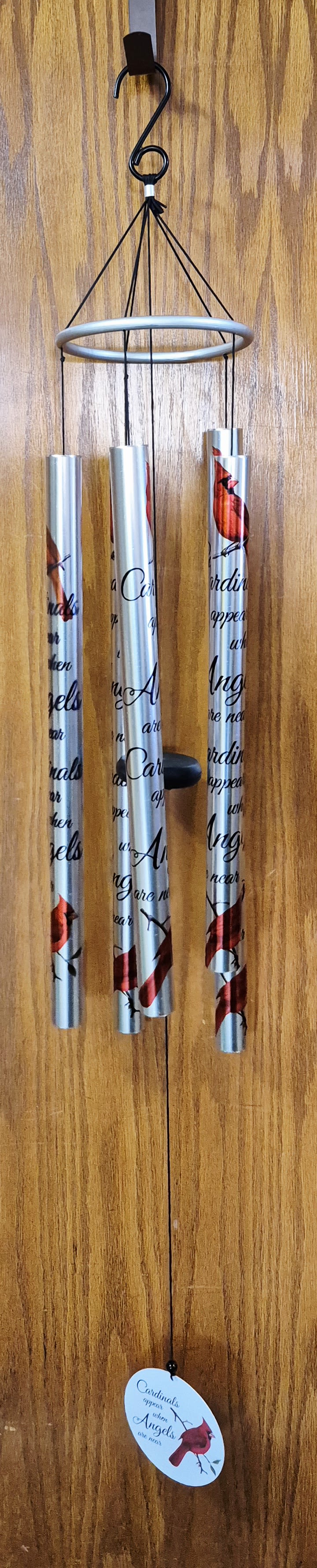 36" Cardinals Appear Memorial Wind Chime - A tall, reflective wind chime emblazoned with vivid red cardinals offers a comforting focal point for sympathy and funeral tributes or a quiet "thinking of you" gift. This 36" memorial wind chime - printed with the line "Cardinals appear when Angels are near" - turns gentle sound and imagery into a meaningful reminder of love and presence, making it appropriate for Memorial Day remembrances as well as everyday moments of solace.  The piece features brushed silver metal tubes printed with deep red cardinal illustrations and flowing black script, suspended from a circular ring by black cords with a central striker to create soft, melodic tones. A matching round hanging sign and printed oval tag repeat the cardinal artwork and sentiment; decorative beads and a sturdy hanging cord complete the design. For display, choose the minimalist black metal easel stand (Deluxe option) or hang the chime from a porch hook, indoor bracket, or included cord - its neutral finish and narrow profile suit sheltered outdoor spaces and interior corners alike.  Give this wind chime as a keepsake to honor someone who has passed, to express "I'm sorry," or simply to let a friend know you're thinking of them; the recipient will find comfort each time the chime rings.  Ordering note: select the Deluxe option to include the metal easel stand for presentation (stand price included in Deluxe).