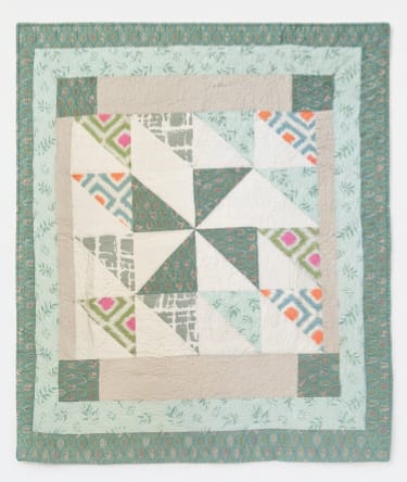 Patchwork quilt with teal, cream, and patterned geometric blocks